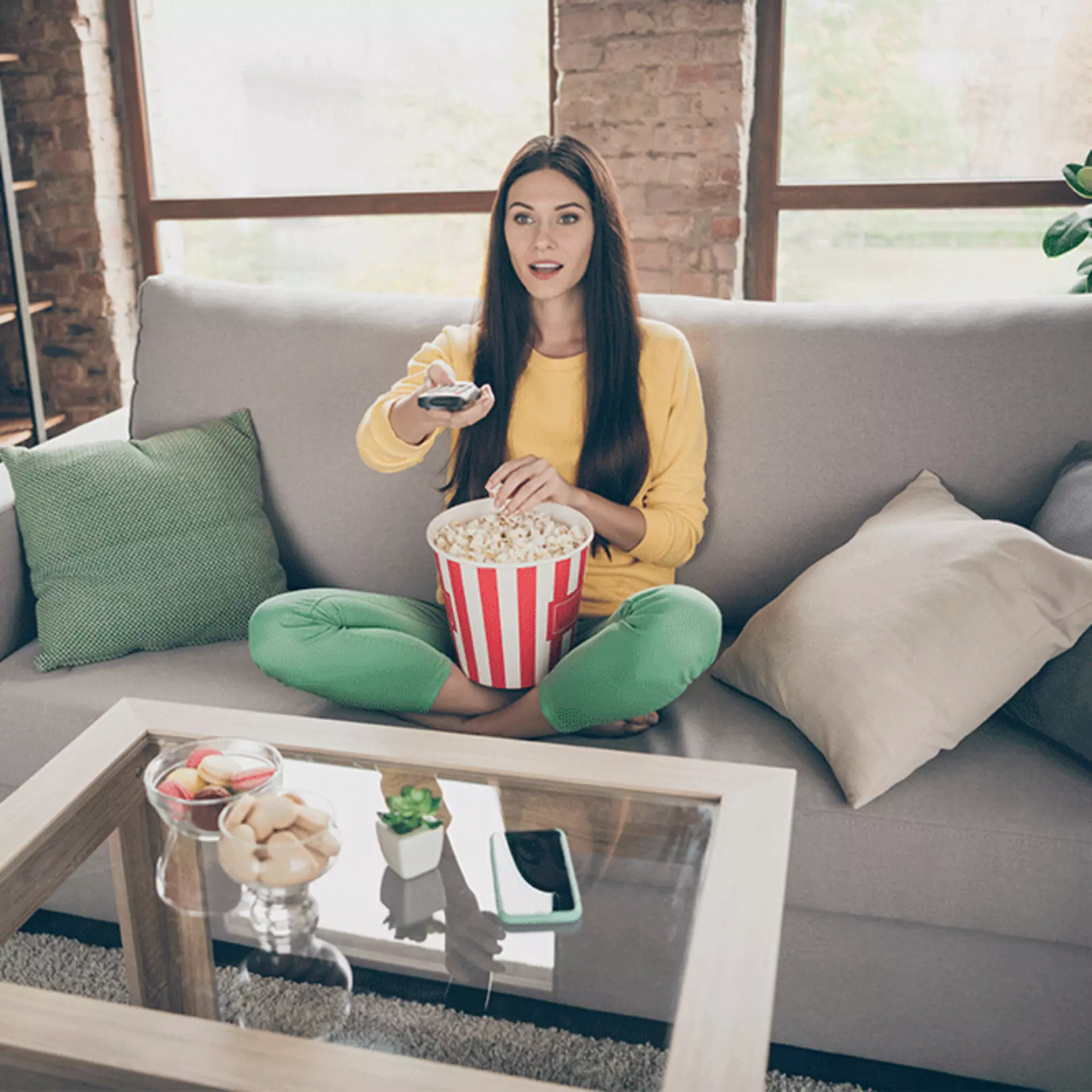 Mädchen sitzt mit Popcorn auf dem Sofa