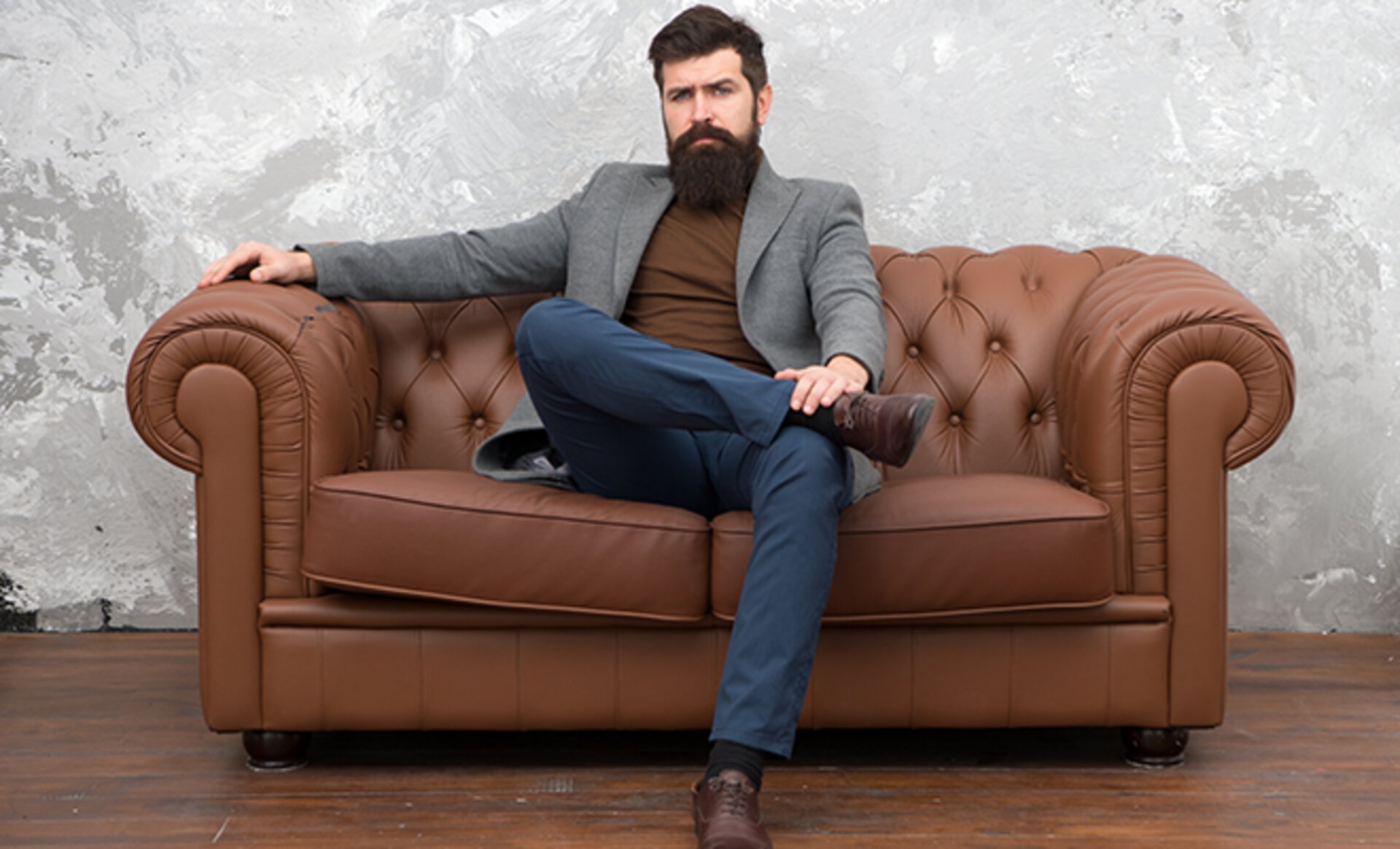 Mann mit Vollbart sitzt auf einem braunen Ledersofa von Möbel Inhofer