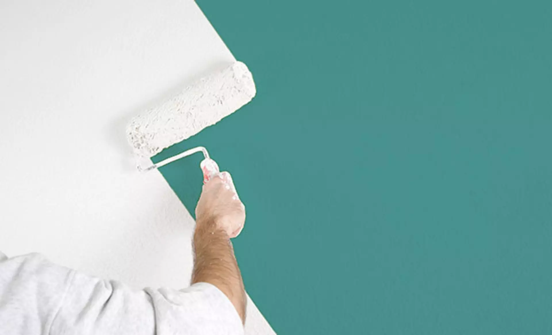 Eine Person die eine Wand Weiß streicht 