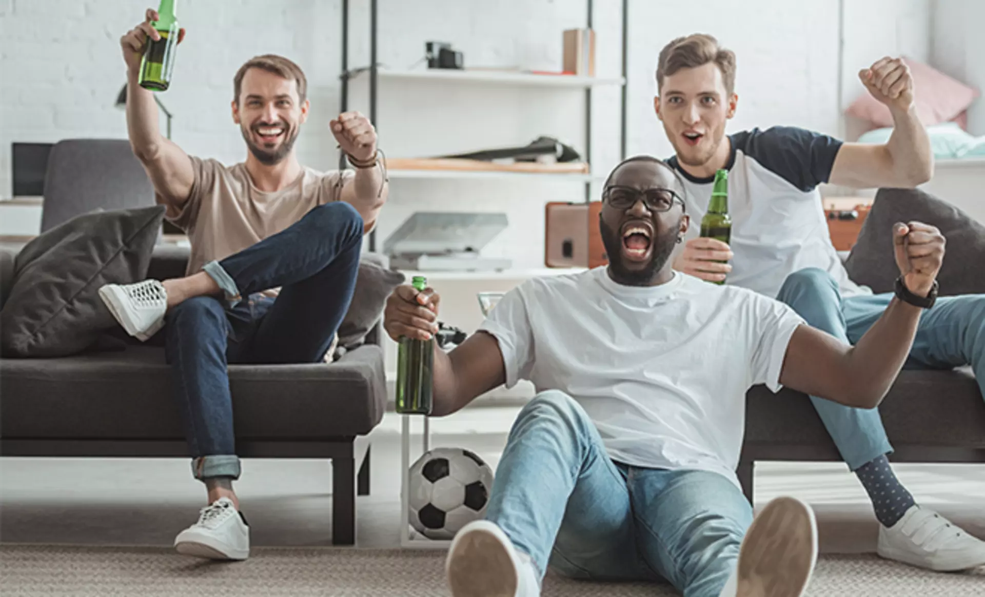 Drei Männer sitzen gemeinsam im Wohnzimmer und schauen Fußball von Möbel Inhofer