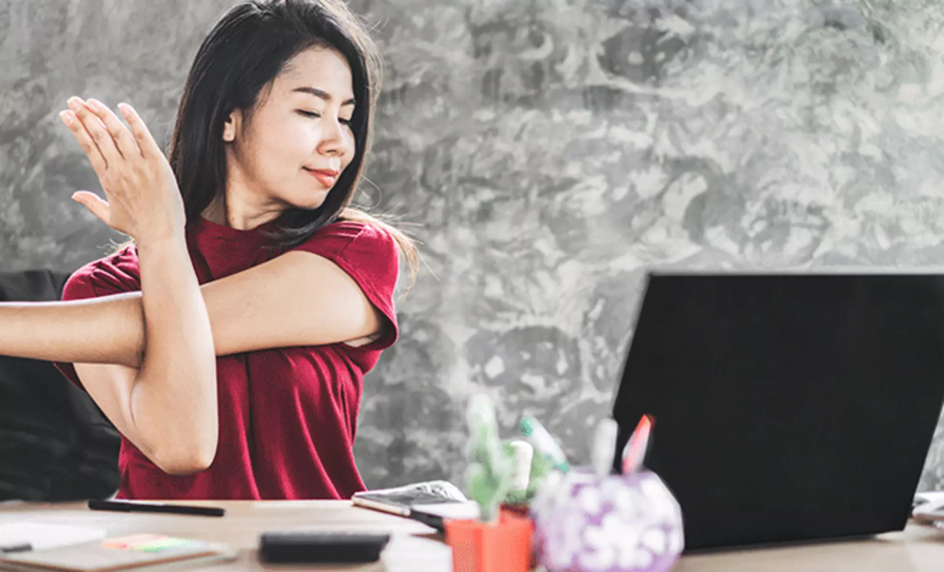 Frau, welche am Schreibtich sitzt und sich dehnt