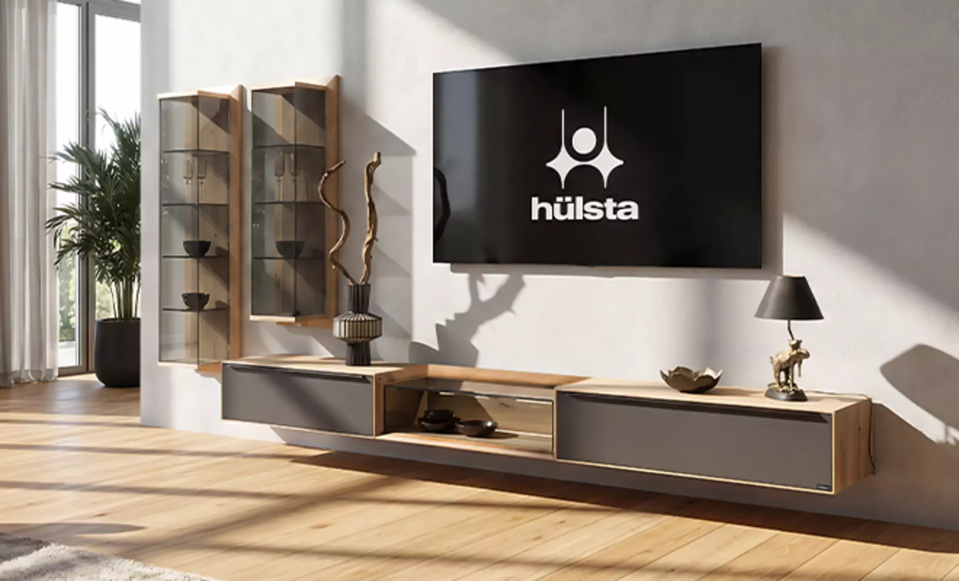 Die Wohnwand Madera von Hülsta mit Ihren Massivholz und Glaselementen an einer grauen Wand.