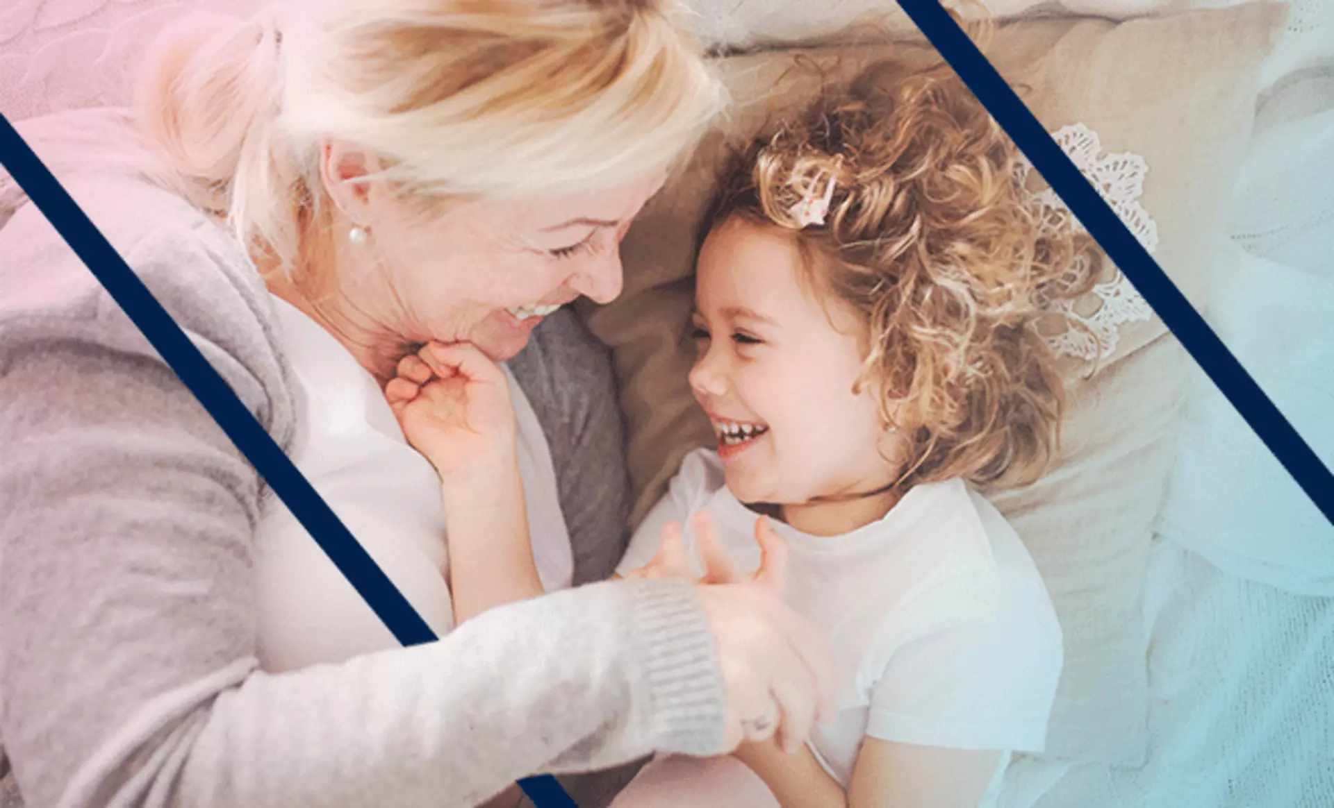 Großmutter und Enkelin kuscheln fröhlich im Bett.