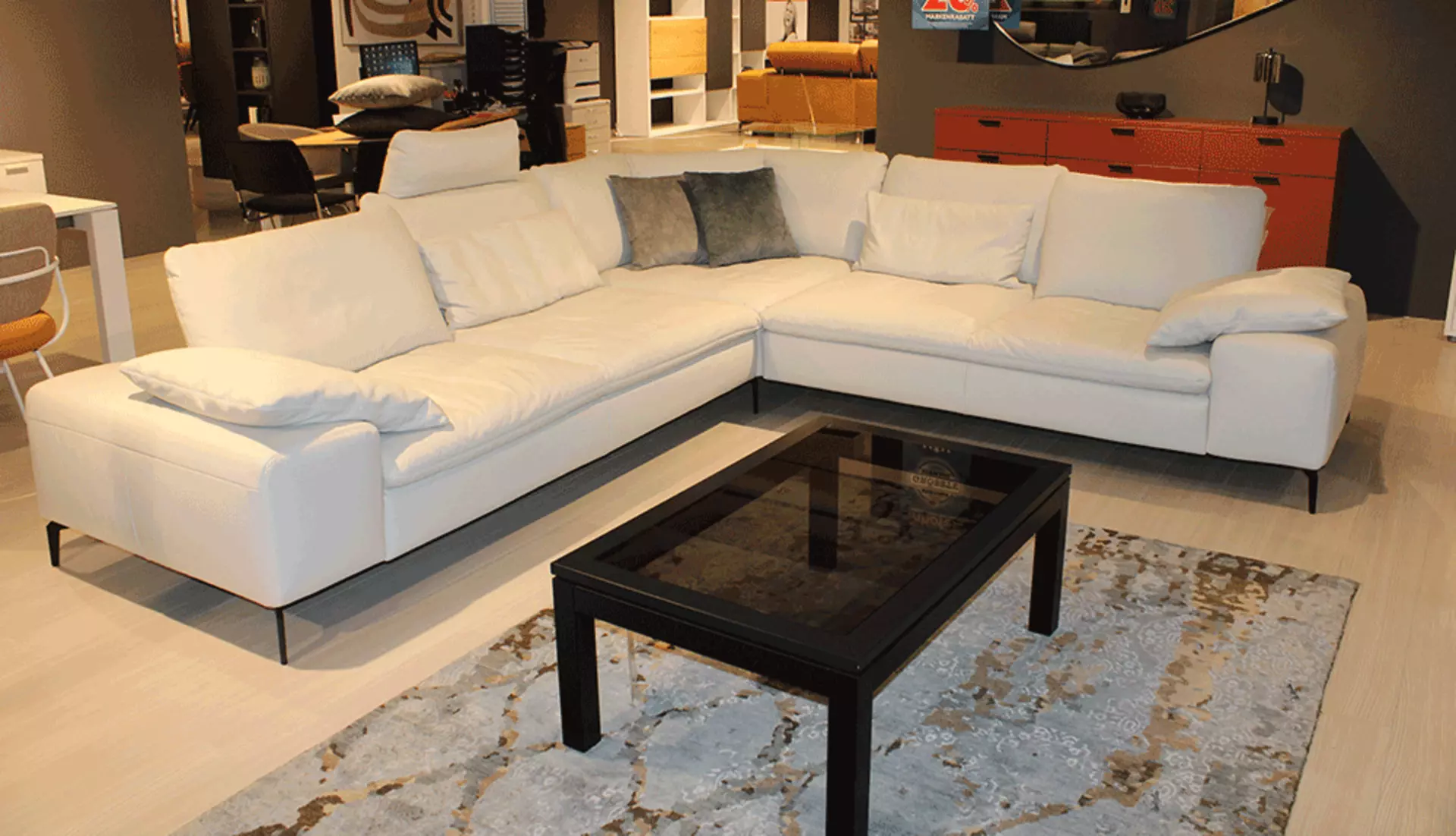 Ein Großer Weißer Ecksofa mit einem kleinen Schwarzen Couchtisch 