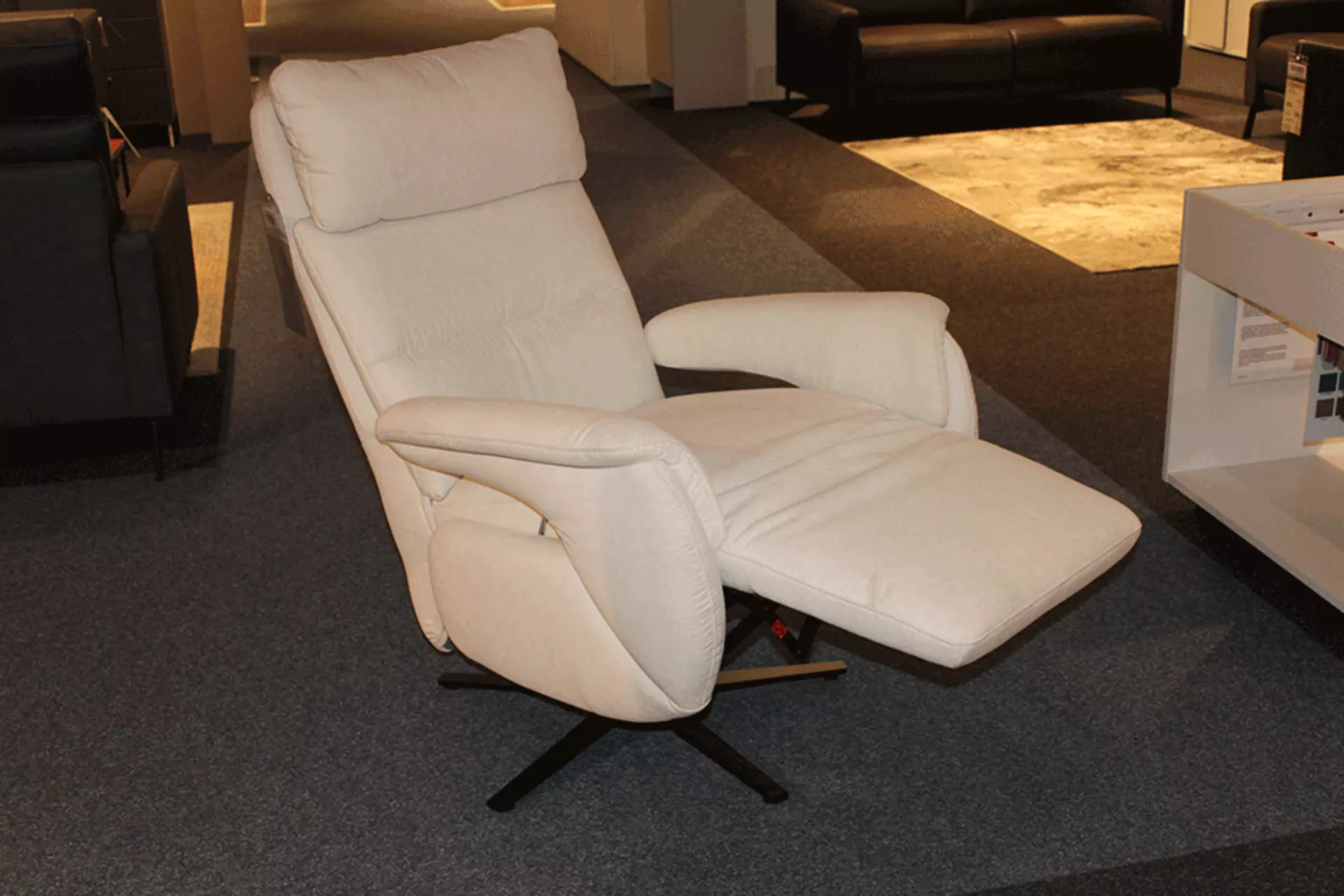 Ein Weißer Liegestuhl das mit schwarzen Metall Füßen ausgestattet ist und die Fußliege nach Oben geht 