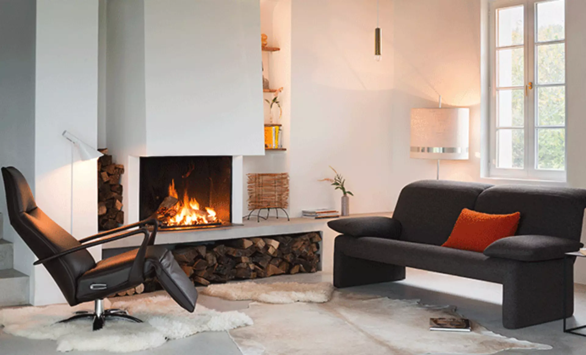 Gemütliches Wohnzimmer mit Kamin und schwarzen Polstermöbel