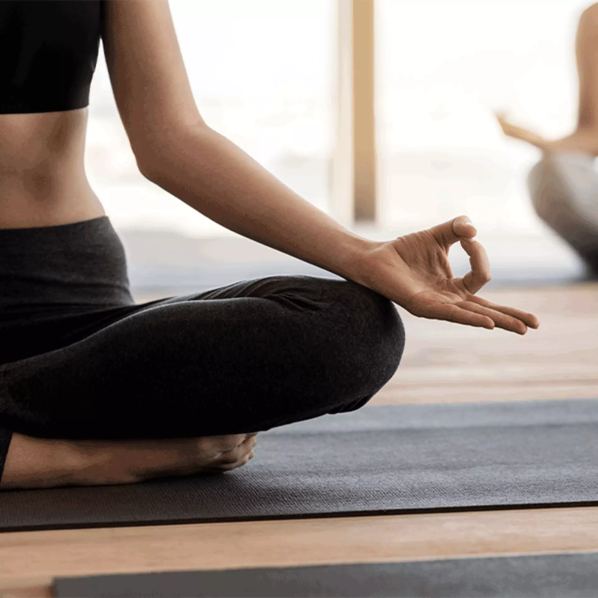 Junge Frau, die auf einer Yogamatte sitzt. 