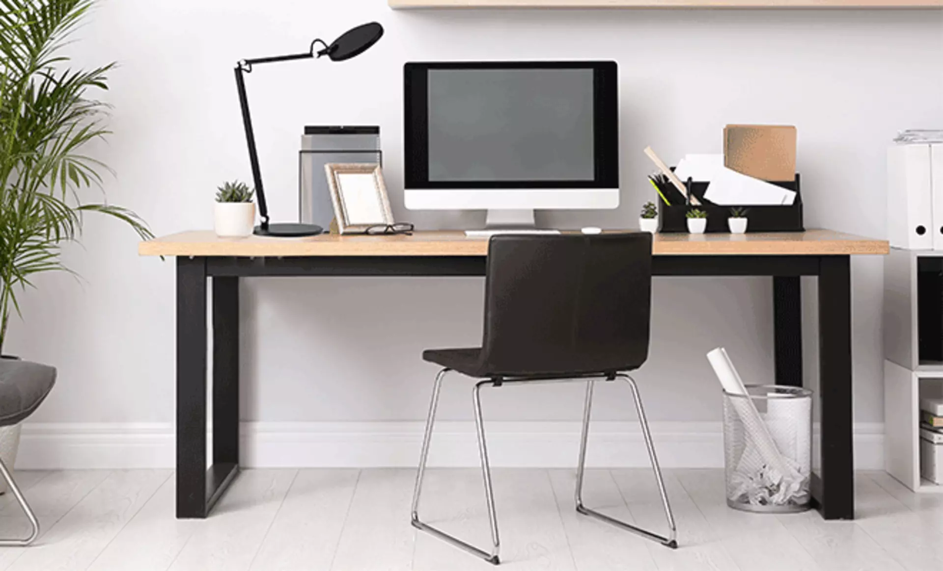 Minimalistisches Bürozimmer das mit einem eckigen Tisch im Raum ist und auf dem Tisch ein Bildschirm steht