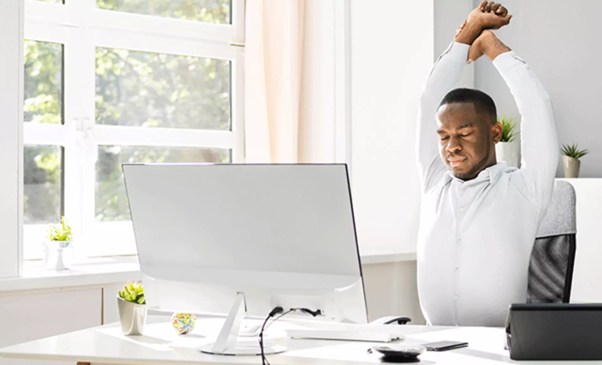 Mann an seinem Schreibtisch am strecken und dehnen