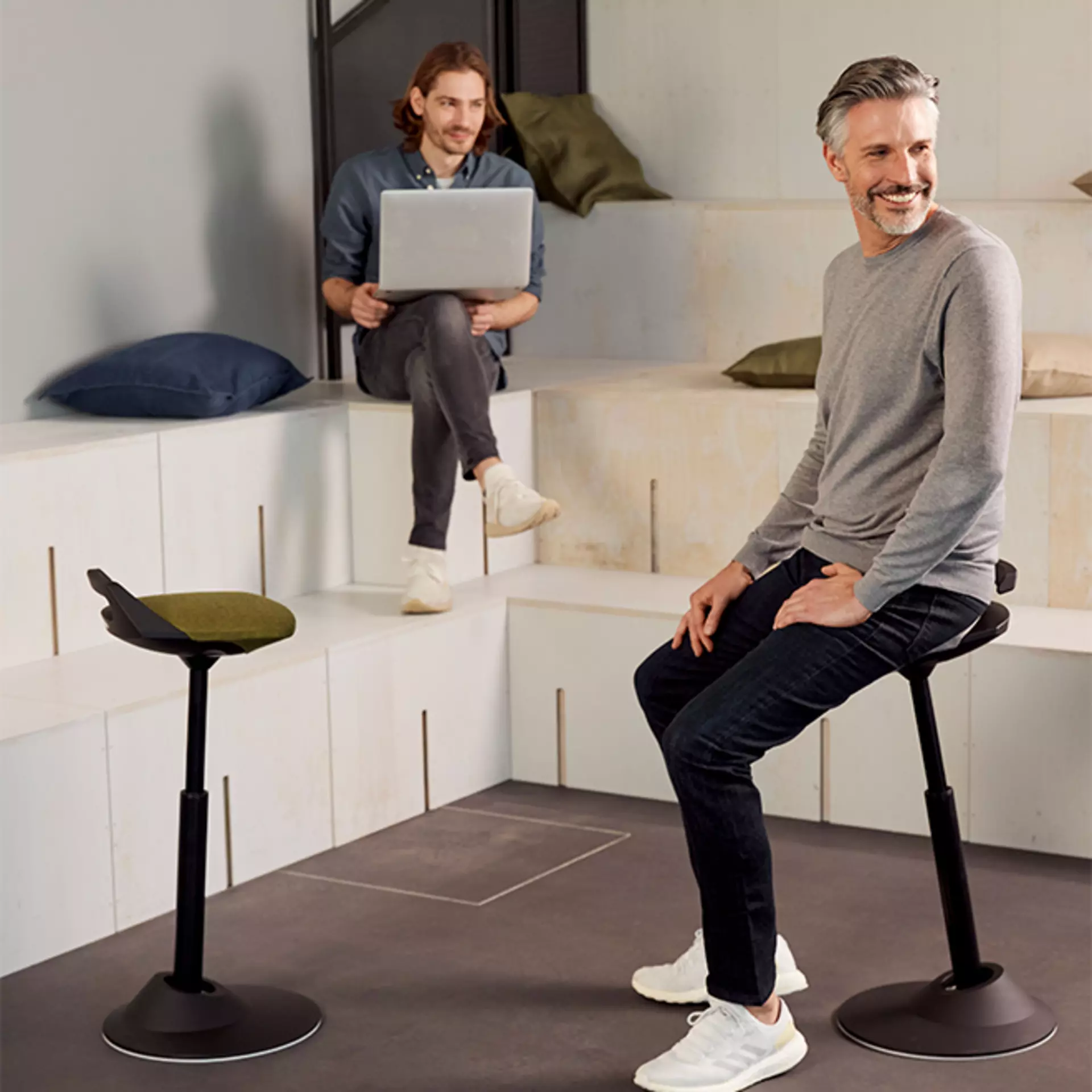 Zwei Männer sind beisammen. Einer lehnt an den Steh-Hocker aeris Muvman an. 