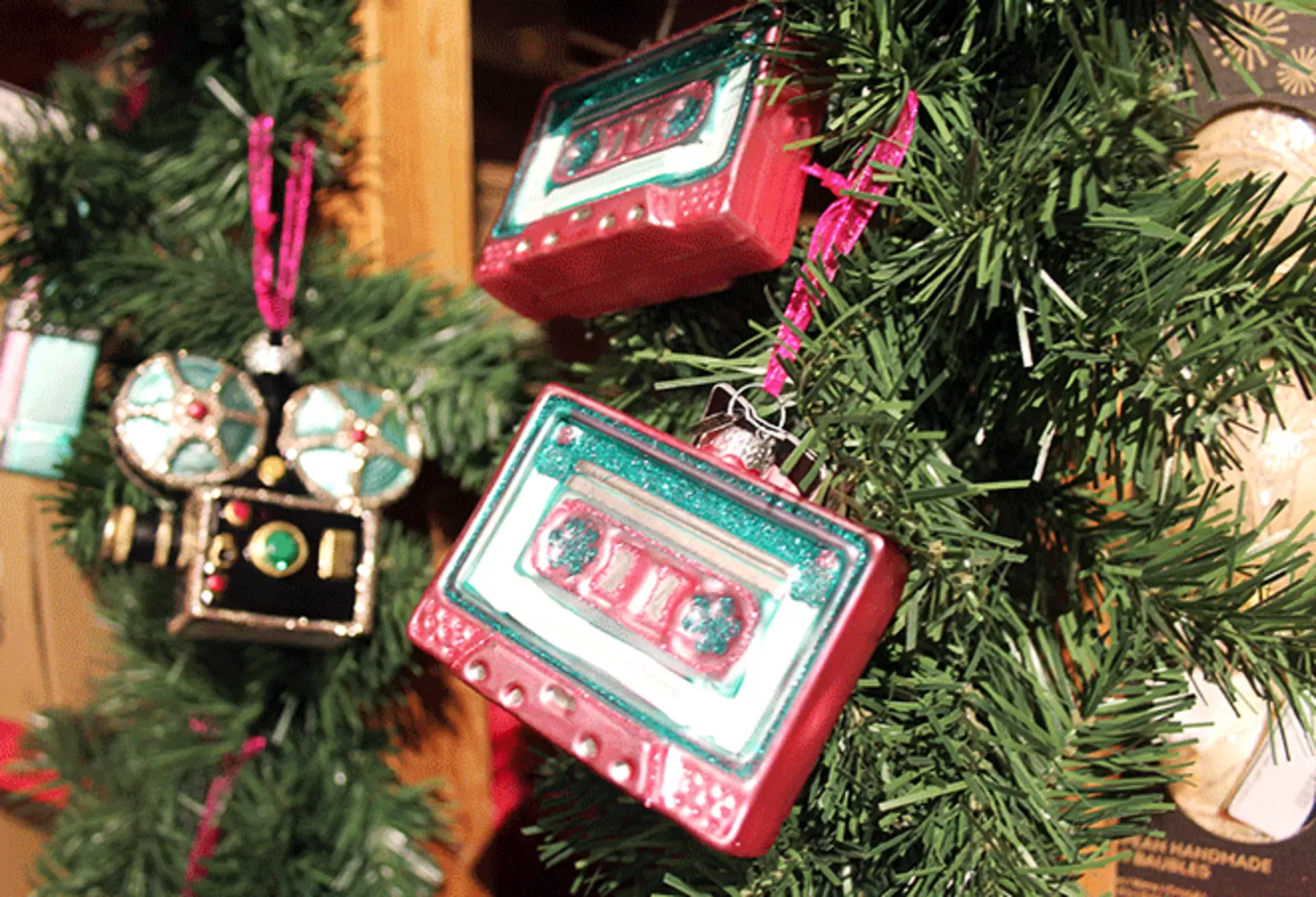 Retro-Weihnachtsbaumschmuck als rote Musikkassette und Glitzer-Kamera am Tannenzweig