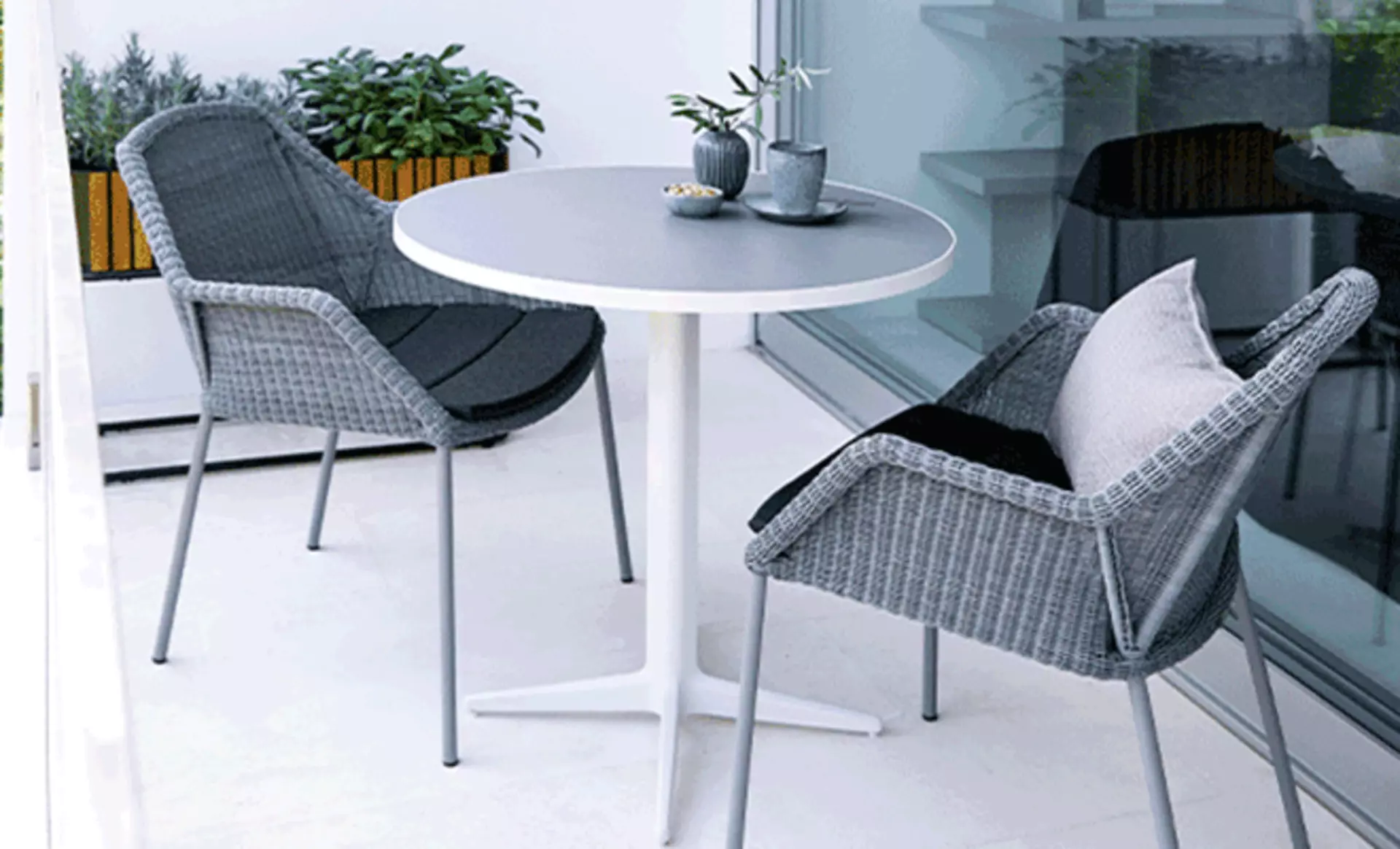 moderne stühle und runder kleiner tisch auf einem balkon in weißer optik