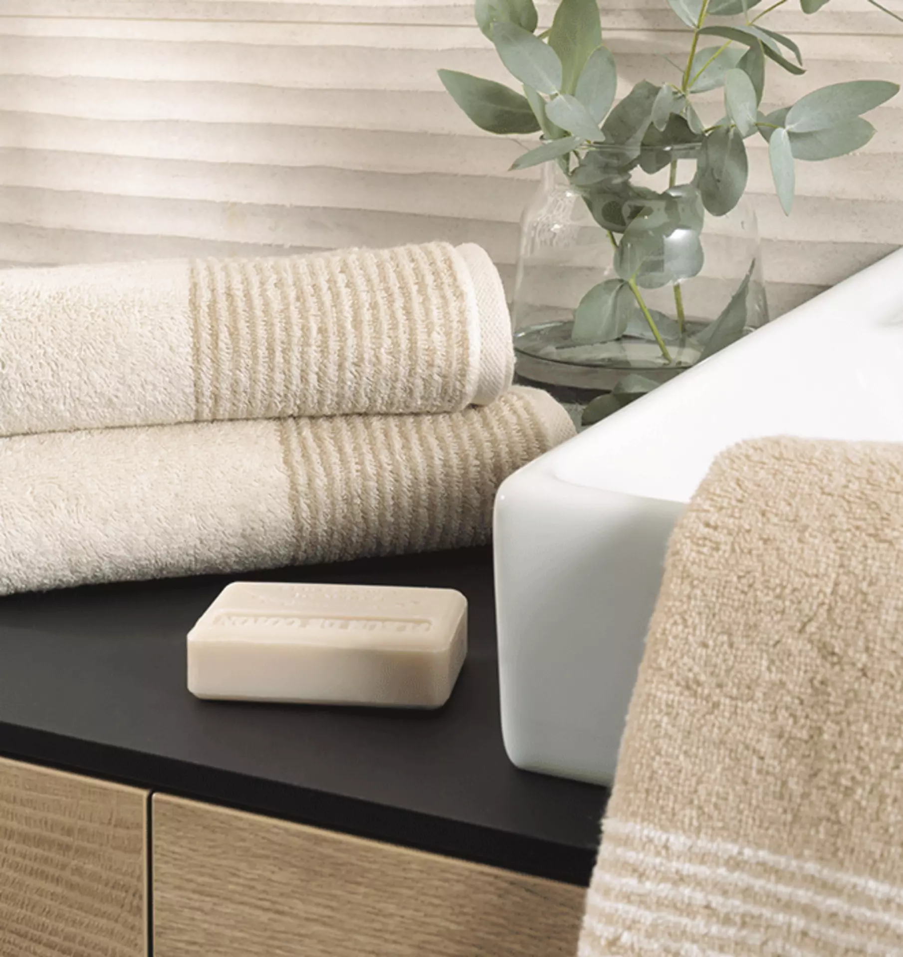 Eine Badezimmer kommode wo zwei beige handtücher drauf liegen und nebenbei noch ein Waschbecken ist