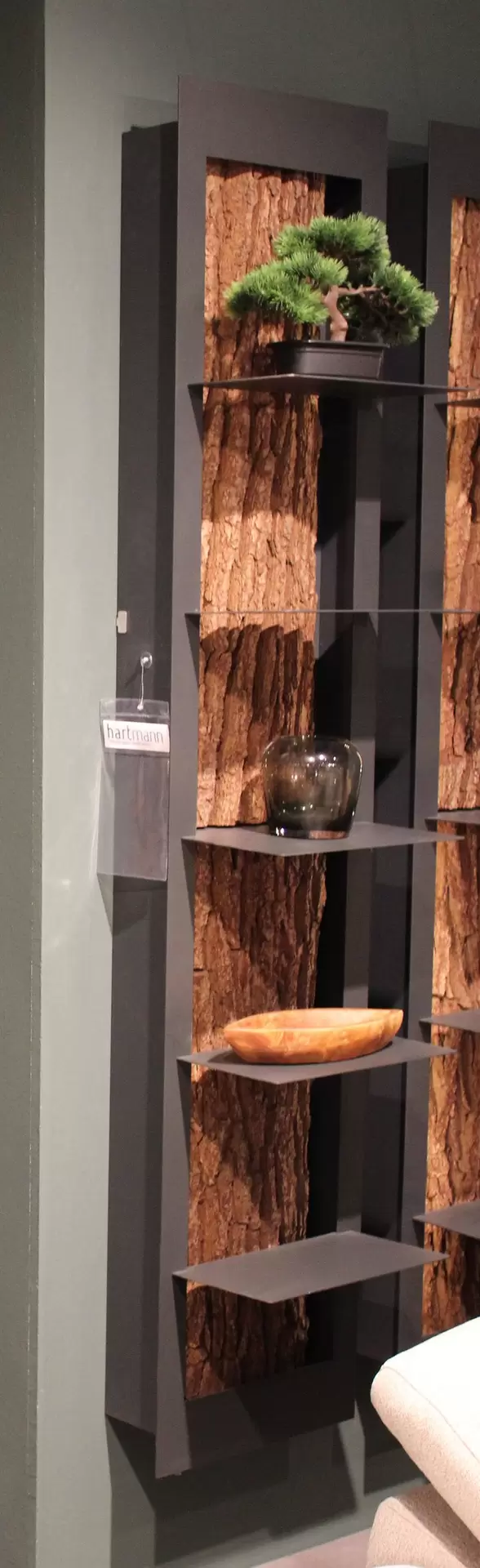 Regal mit schwarz Metallischen Gerüst und einer Baum Rinde in der Mitte