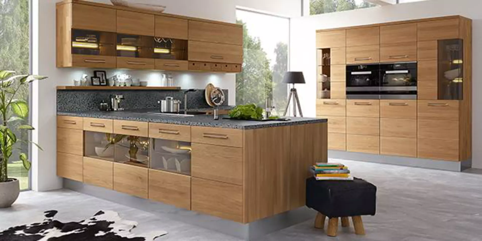 Moderne Küche aus Massivholz und Naturstein-Arbeitsplatte. Die Küche ist in L-Form gestaltet, wobei ein Teil als Kücheninsel den Raum zum Wohnbereich abtrennt. Die edle First-Calls-Küche ist von der Marke Decker.