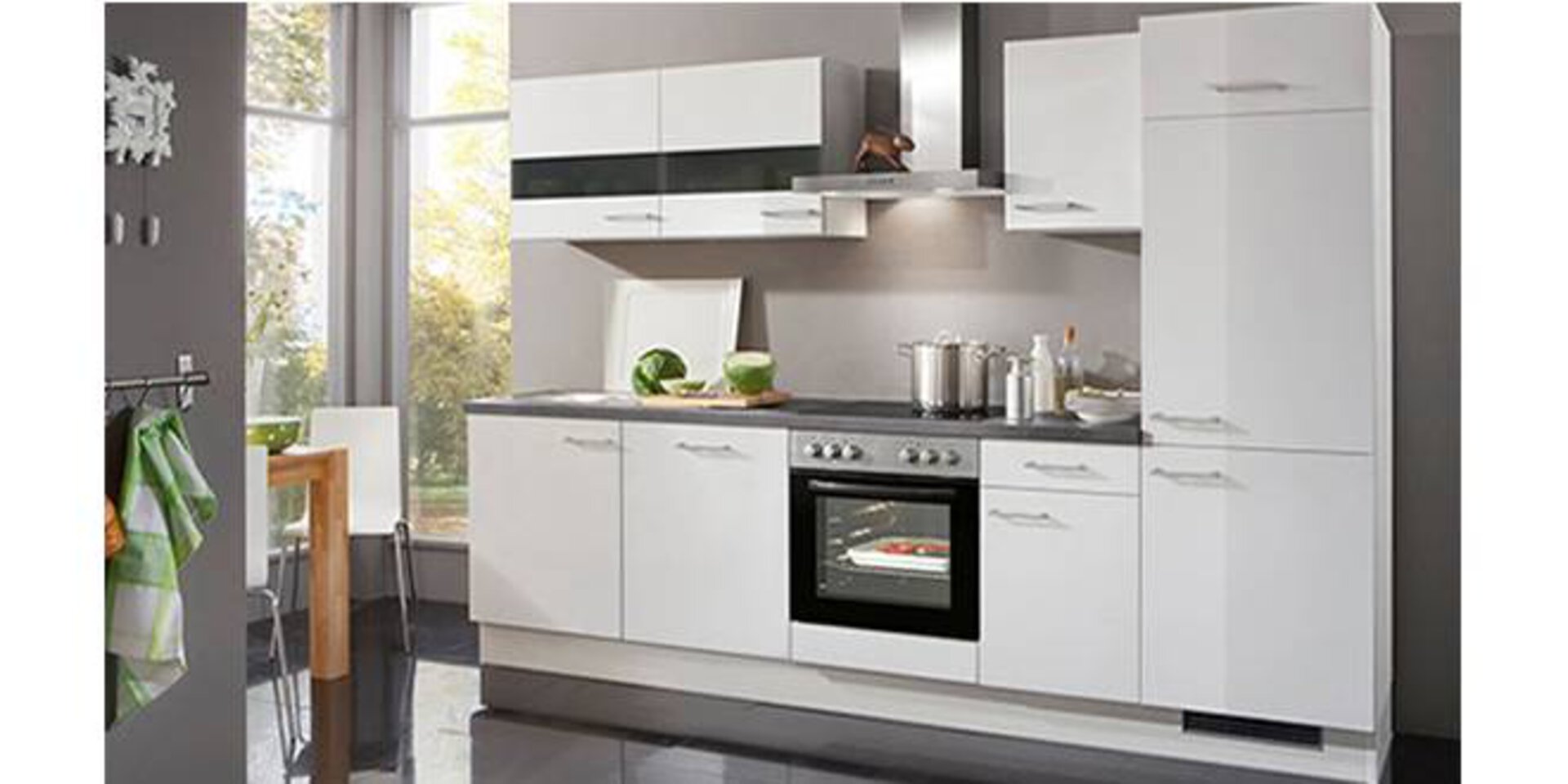 Eine weiße Küchenzeile inklusive Hochschränken zeigt eine typische Kompaktküche.