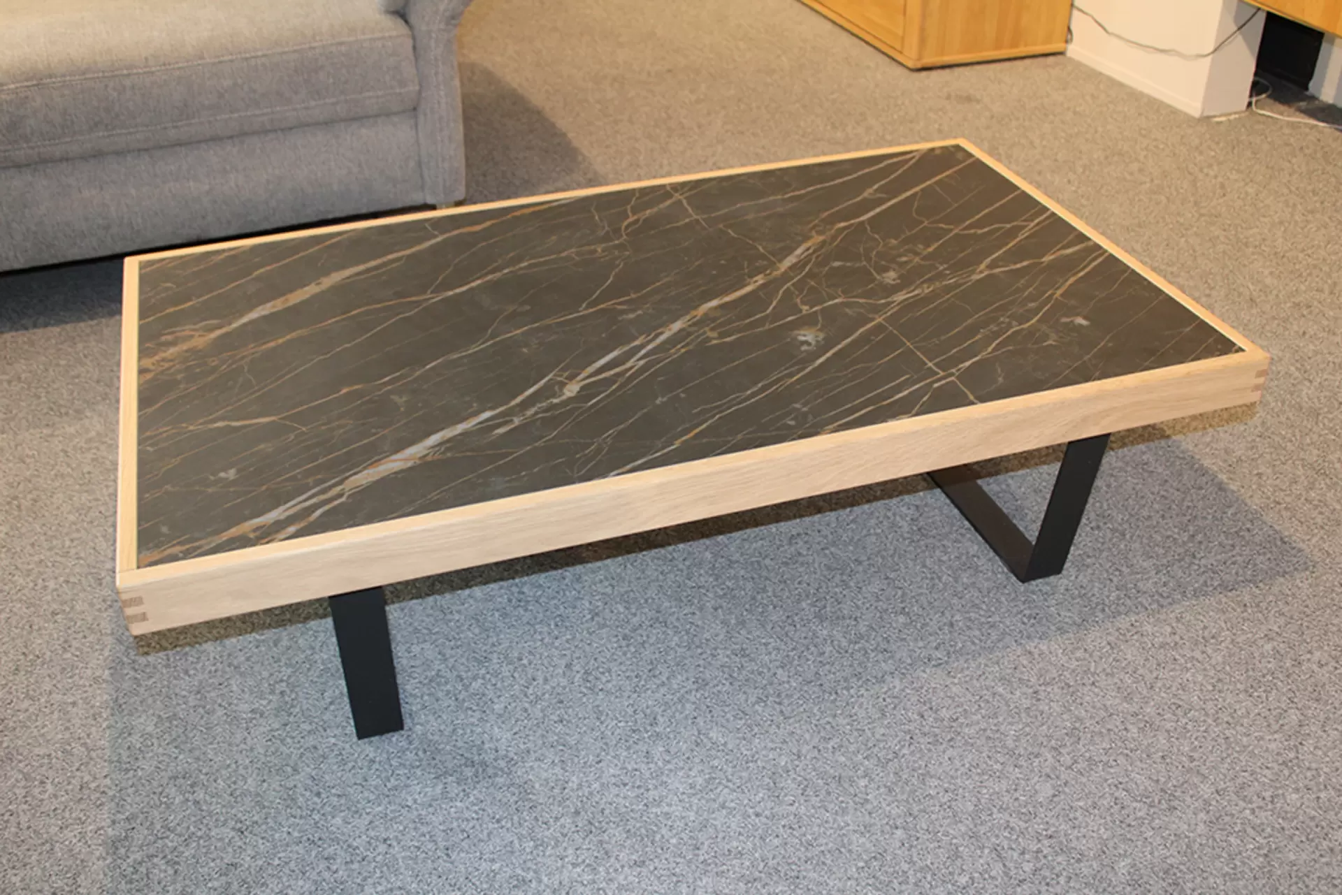 Der Couchtisch TIRANO von Wöstmann aus Holz mit Metallbeinen und Marmor-Platte