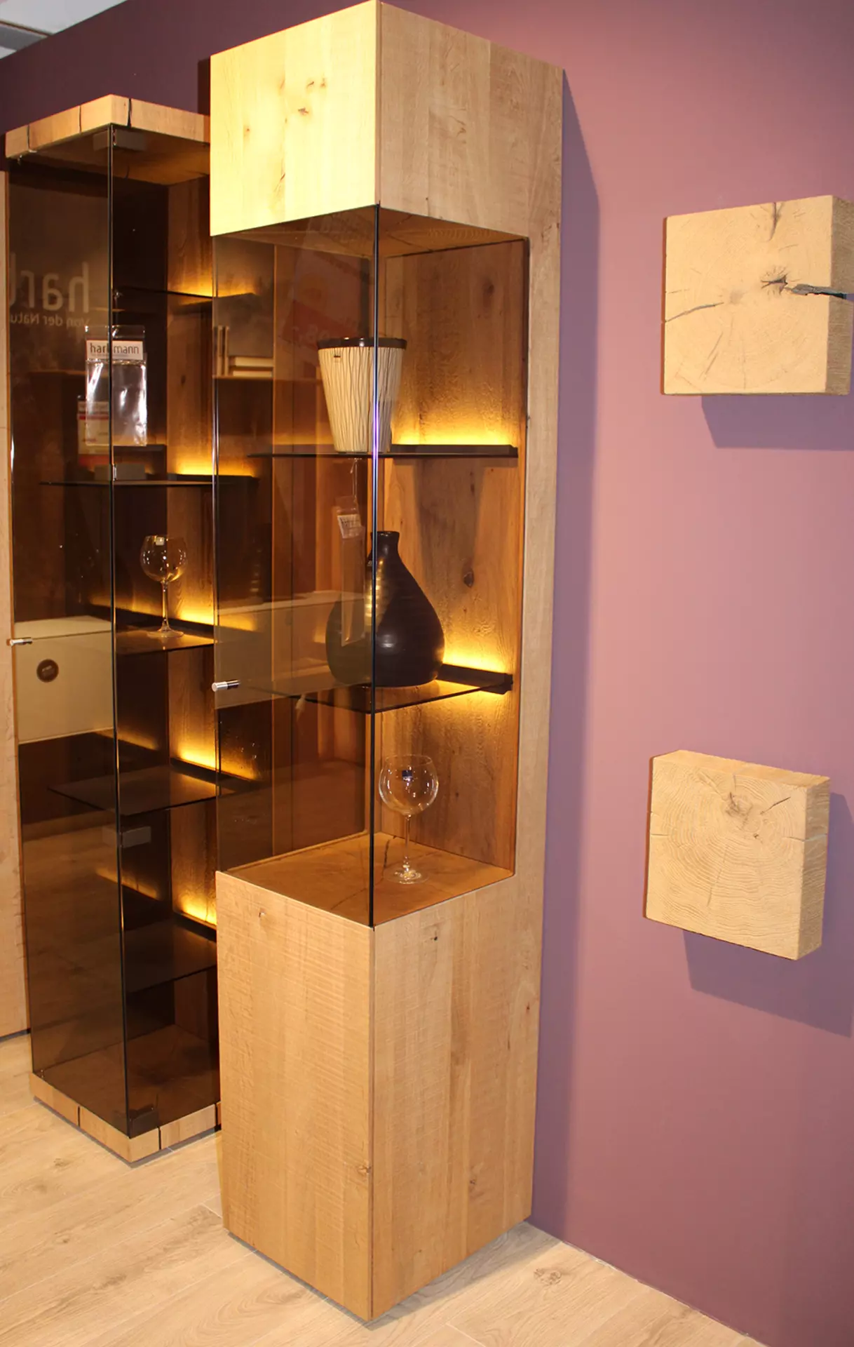 Eine Vitrine in Holzoptik mit Vasen und warmer beleuchtung