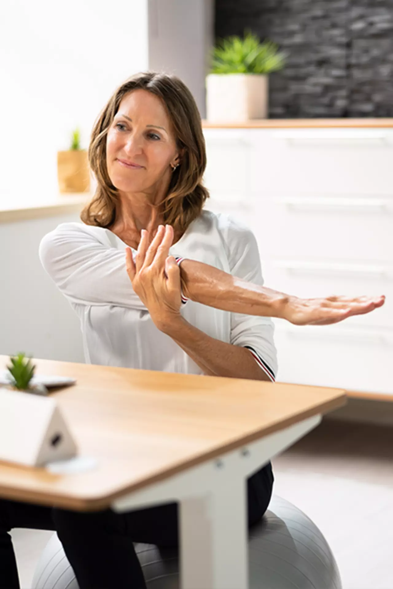 Frau mit langen Haaren macht eine Dehnübung am Arbeitsplatz für die Schultern