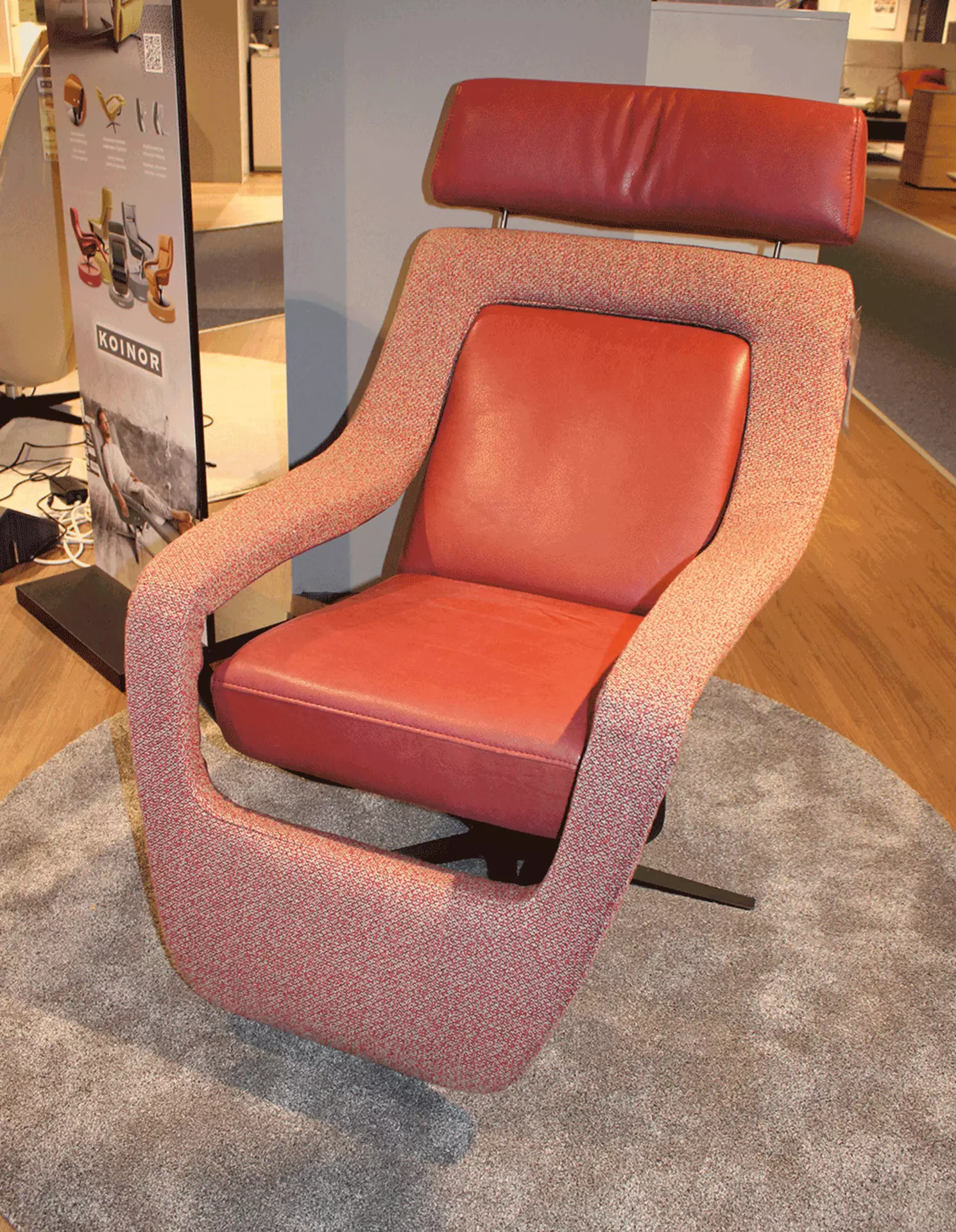 Ein Relaxsessel aus Leder in der Farbe rostrot das mit gekreutzten schwarzen füßen ausgestatet ist 