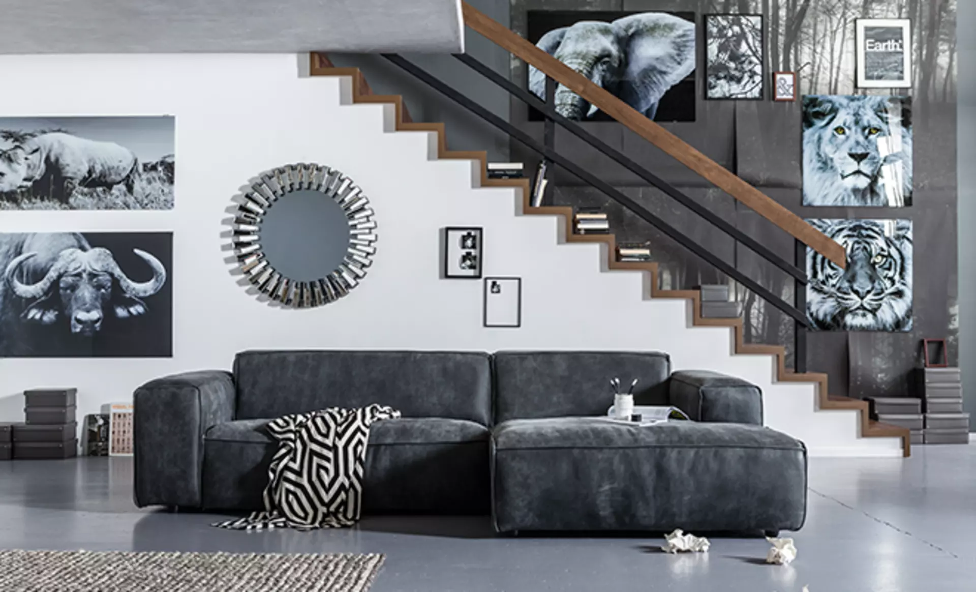Ein dunkel Graues Sofa in dem Mehrere Bilder im Hintergrund an der Wand hängen