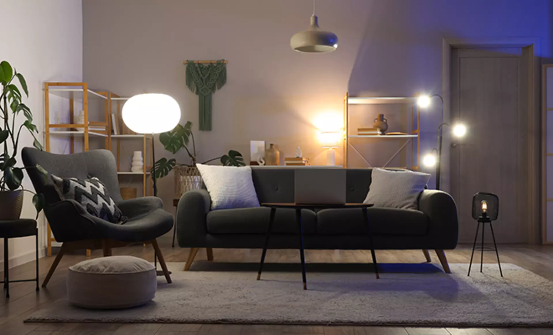 Modernes Wohnzimmer mit zweisitzer Couch und Cocktailseesel zum lesen. Gut ausgeleuchtet mit Akzentleuchten und Stehleuchte. 