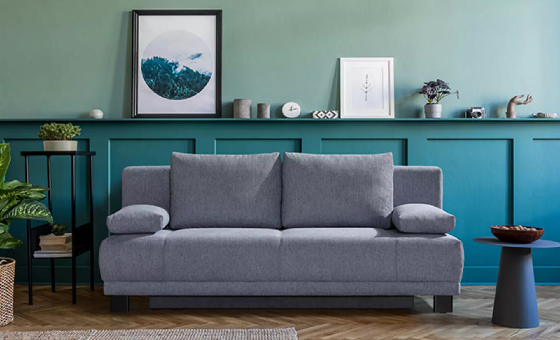 Schlafsofa vor schöner petrolfarbener Wand mit Beistelltischen