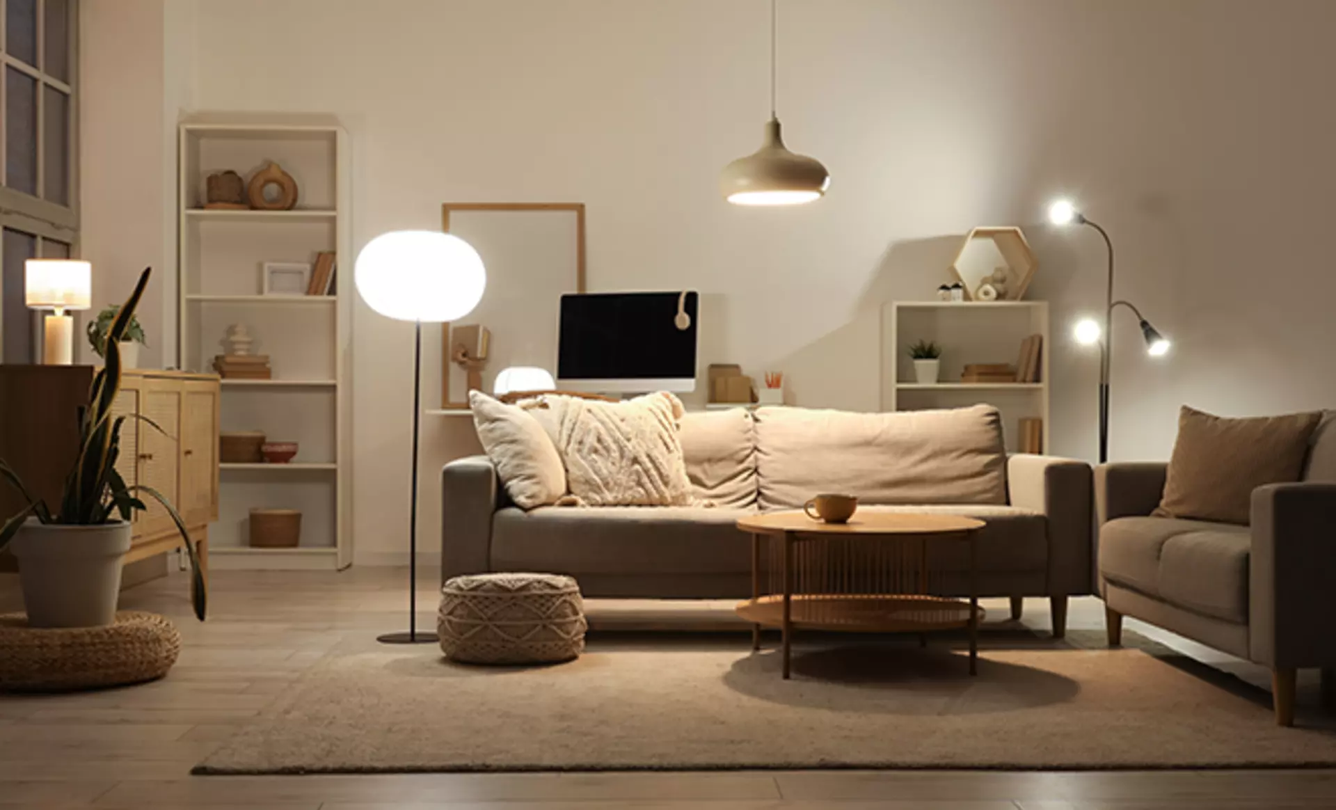 Kleines Wohnzimmer mit zweisitzer Sofa und vielen unterschiedlichen Leuchten