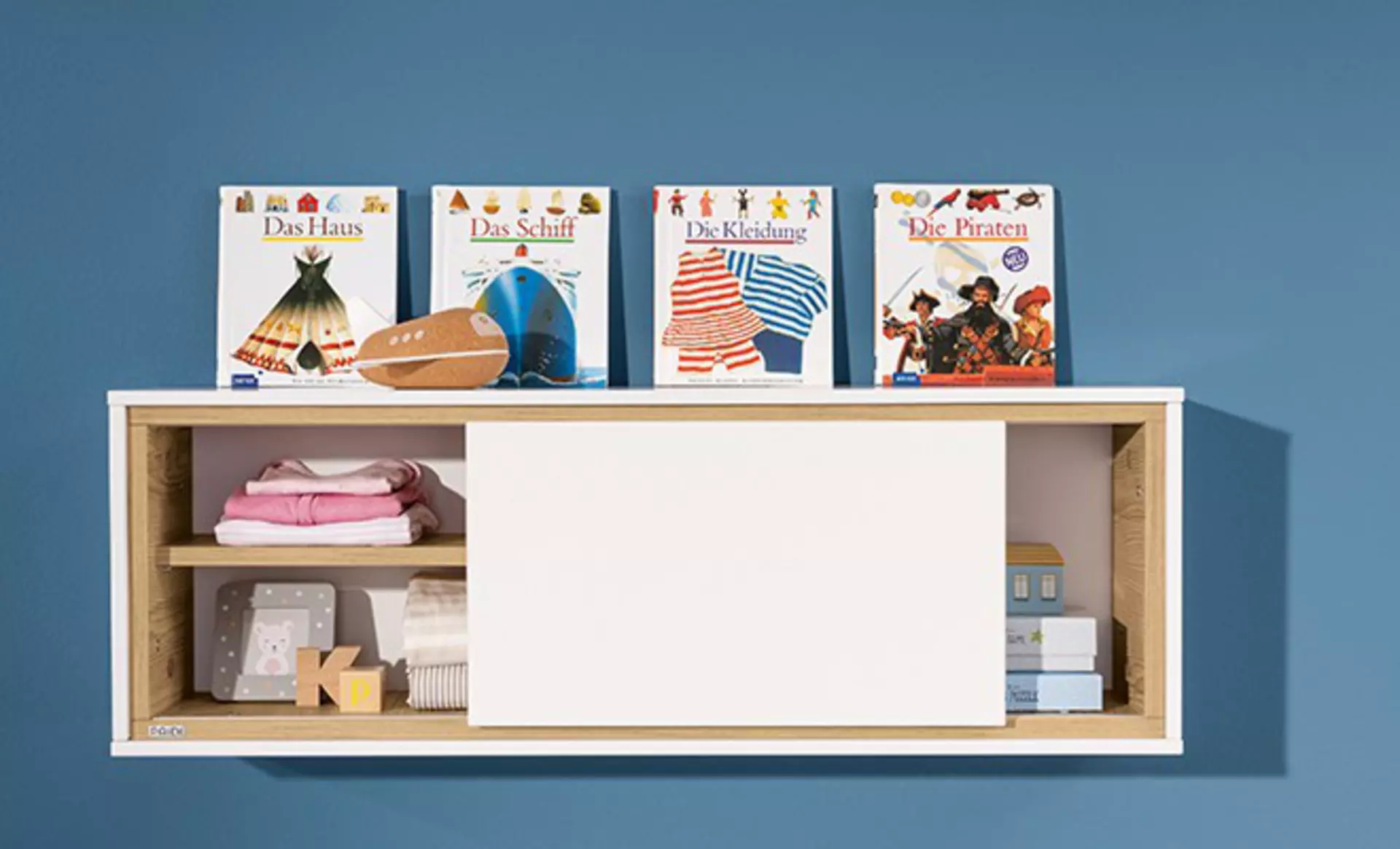 Wandregal im Kinderzimmer mit Büchern und Kleidung