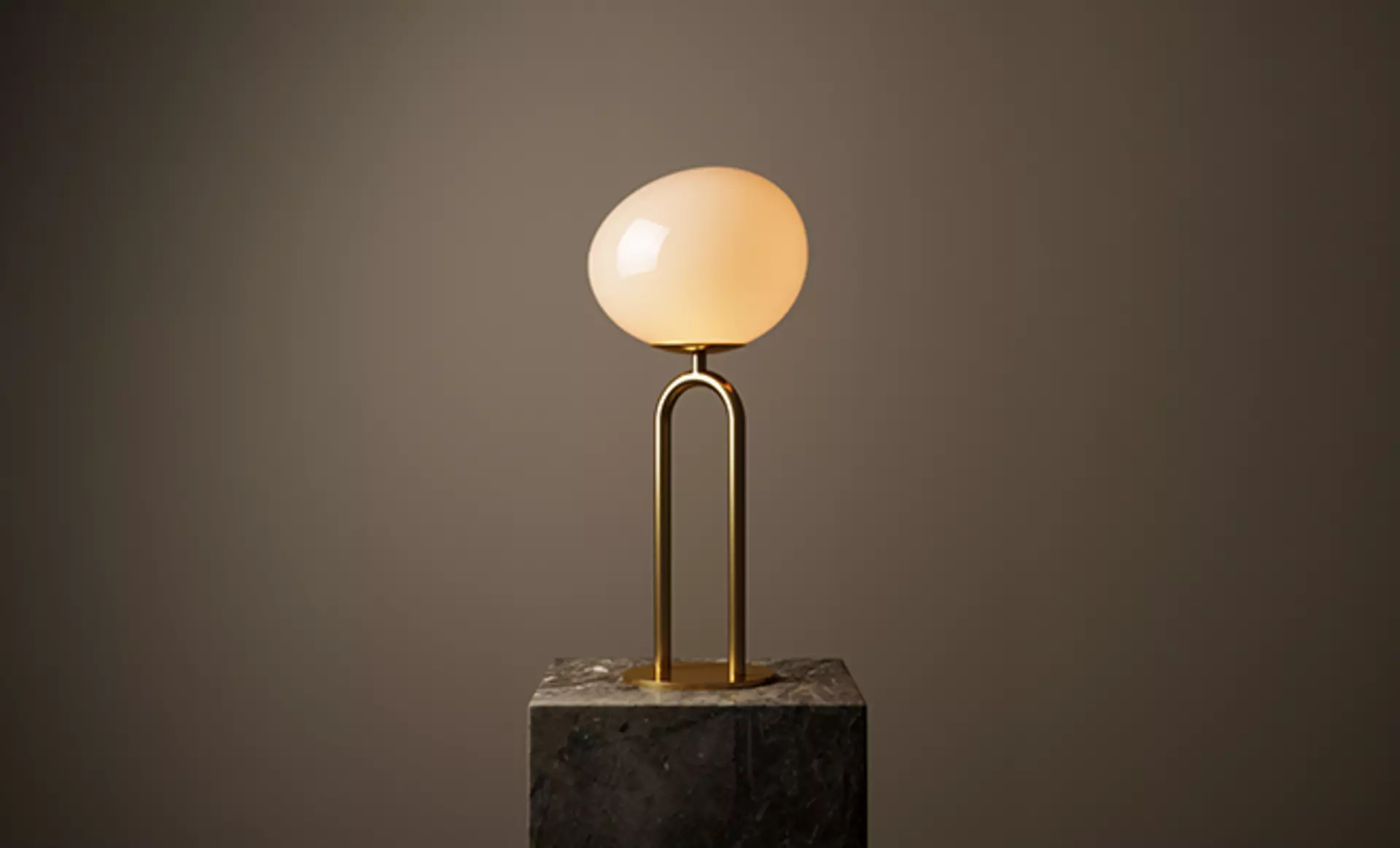 Nordlux schafft mit seiner Shapes Kollektion außergewöhnliche Leuchten. Wie hier zu sehen auf einem Marmor-Sockel vor einer braunen wand