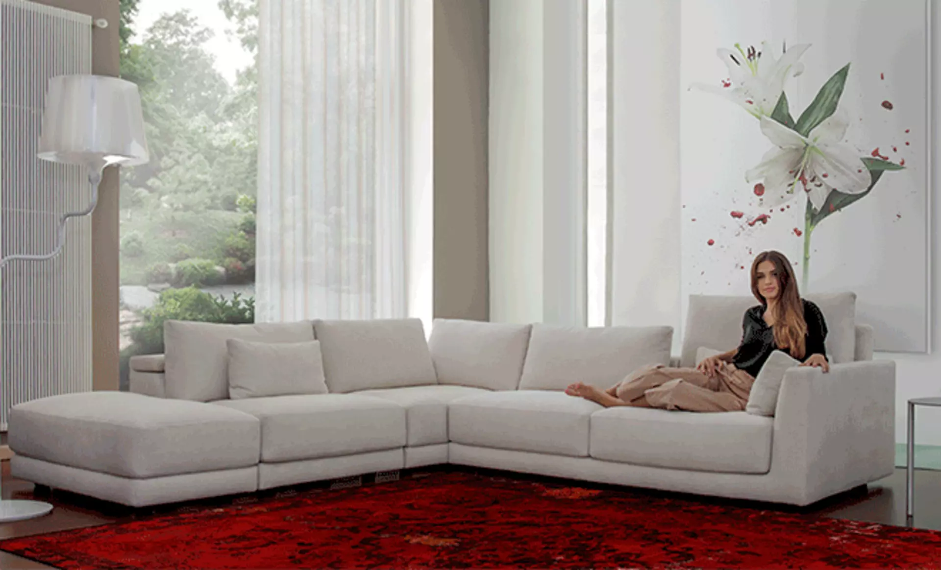 Frau liegt entspannt auf einem großen weißen Sofa von Calia Italia in einem modernen Wohnzimmer.