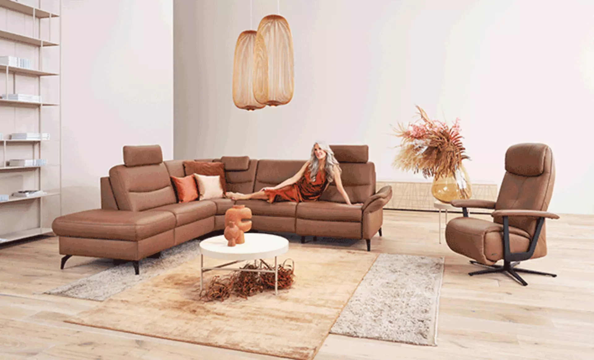 Frau entspannt auf braunem Ledersofa im Boho-Wohnzimmer mit passendem Sessel aus derselben Serie
