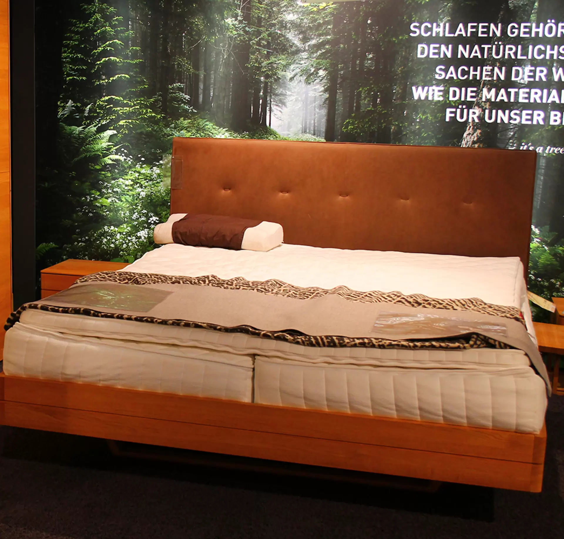 Ein Boxspringbett + Nachtkonsole von Team 7 aus massivem holz und in braunem Stoffbezug