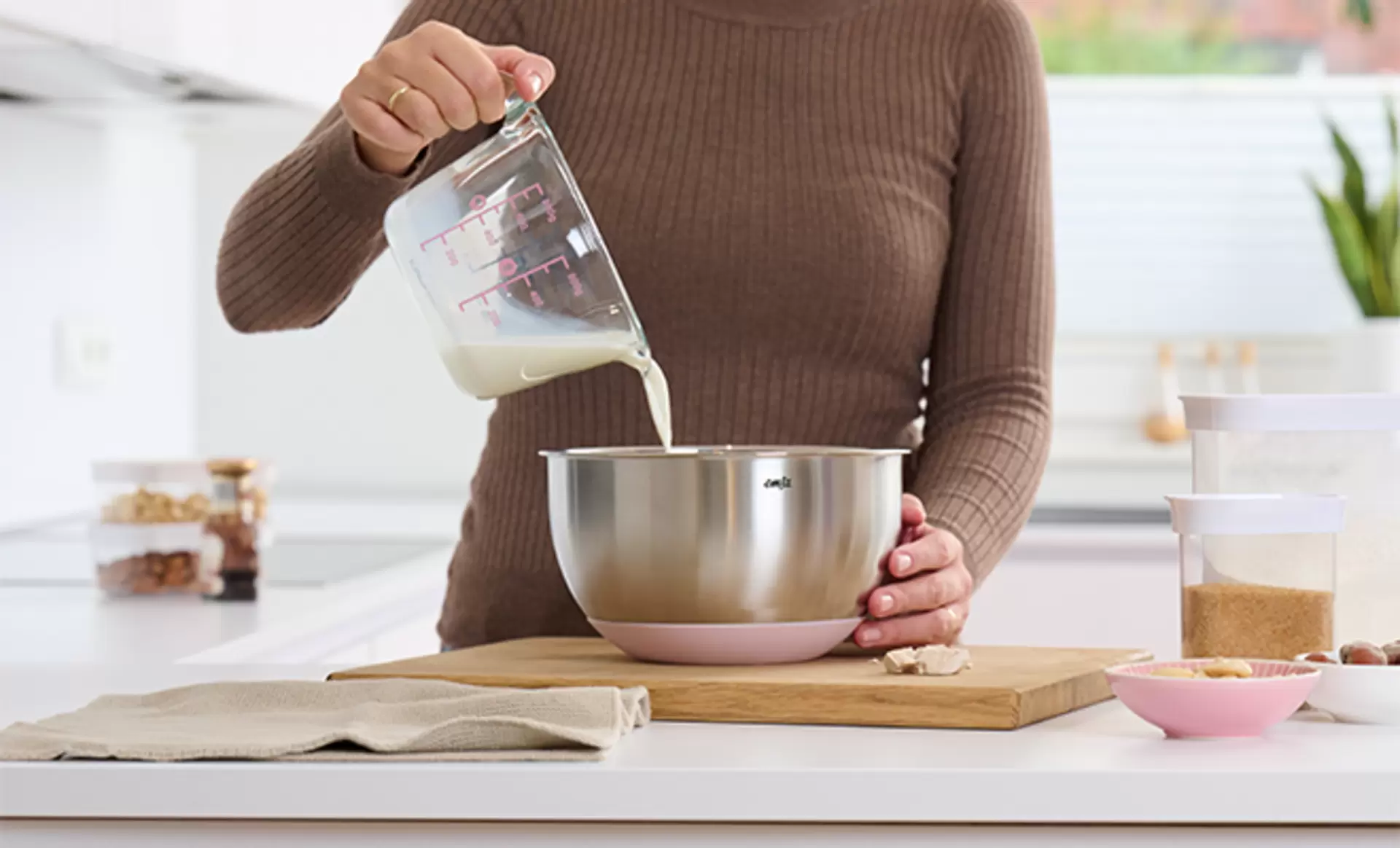 Praktische Emsa Schüssel aus Edelstahl bei der eine Frau gerade Milch mit einem emsa Messbecher einfüllt