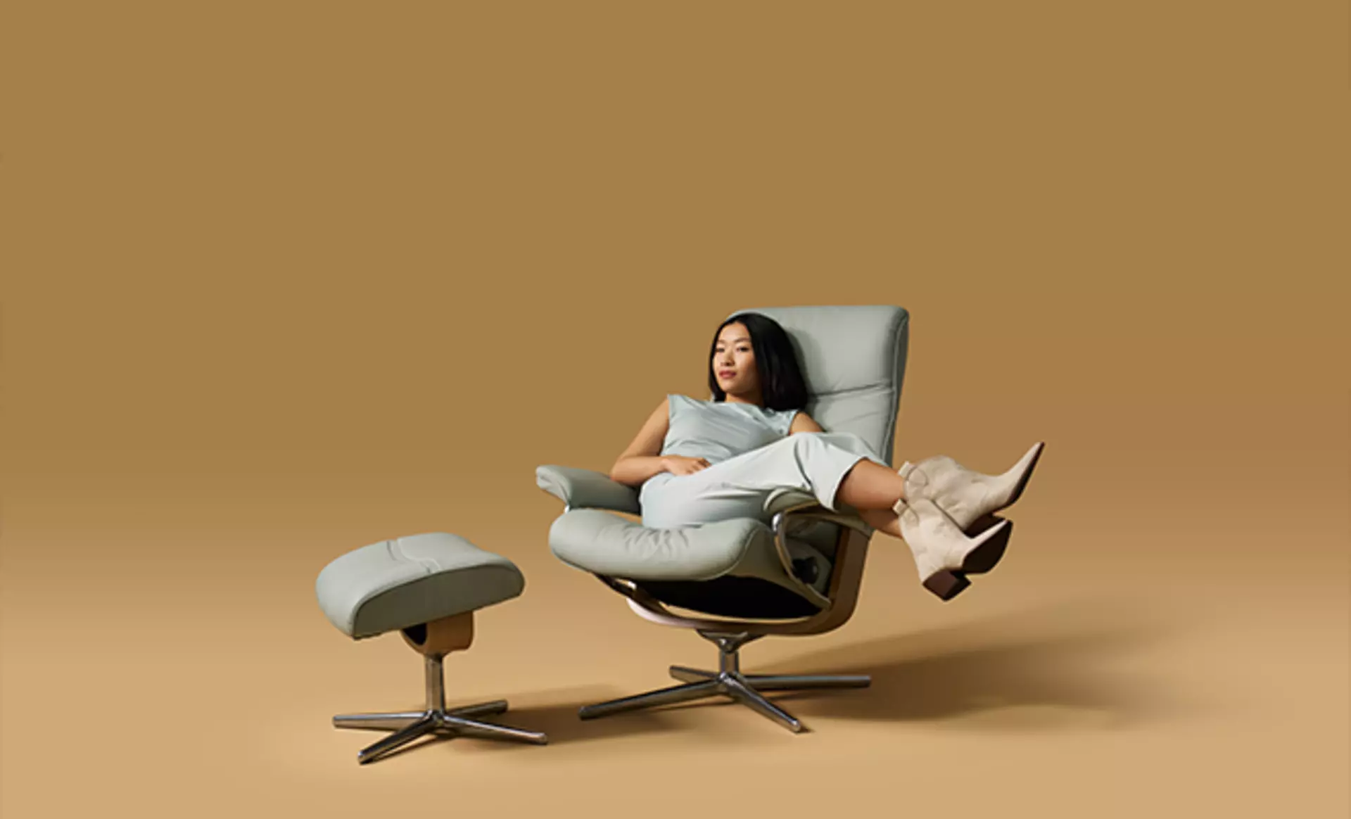 Eine Frau sitzt im Stressless Philip Sessel in hellblauem Paloma Leder in einem Studio