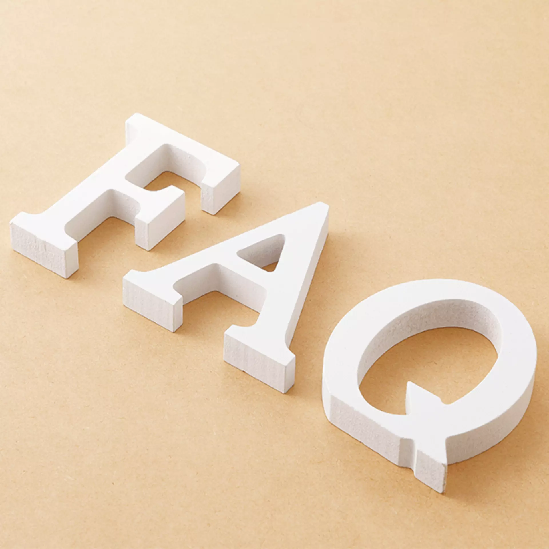 Weißer FAQ Schriftzug auf beigem Hintergrund