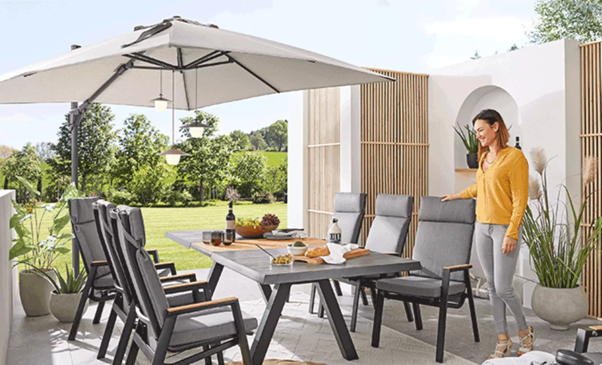 Sonnenschirm über einem Esstisch im Freien der mit lichtern dekoriert ist