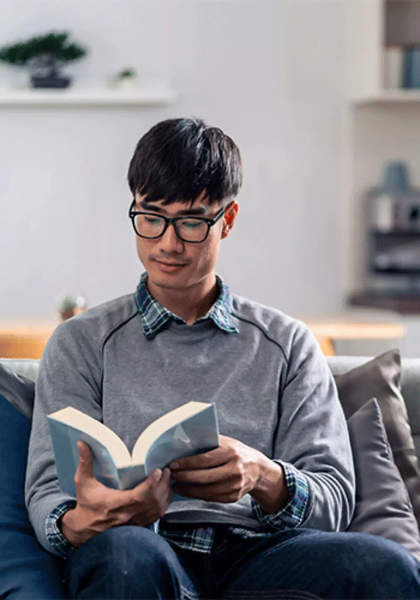 Asiatischer Mann beim Lesen eines Buches auf der couch