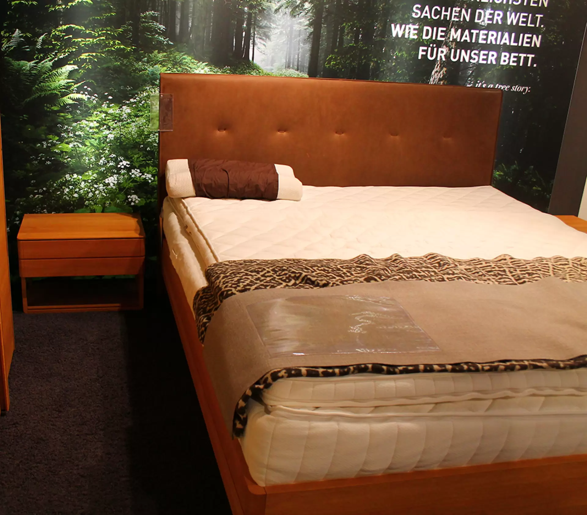 Ein Boxspringbett + Nachtkonsole von Team 7 aus massivem holz und in braunem Stoffbezug