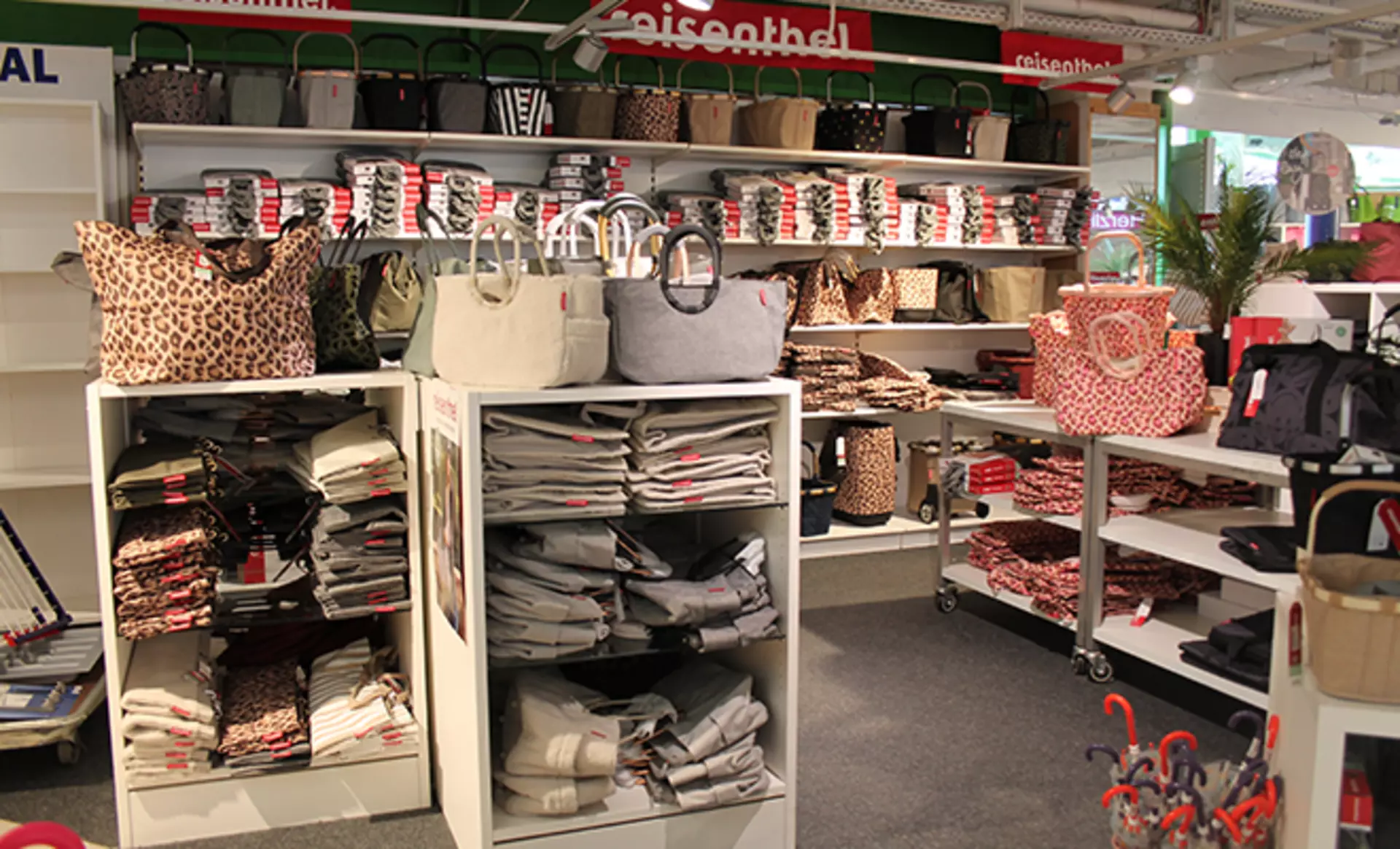 Reisenthel Verkaufsfläche mit einer großen Auswahl an Einkaufstaschen, Körben und Accessoires in verschiedenen Farben und Mustern in Regalen ausgestellt.