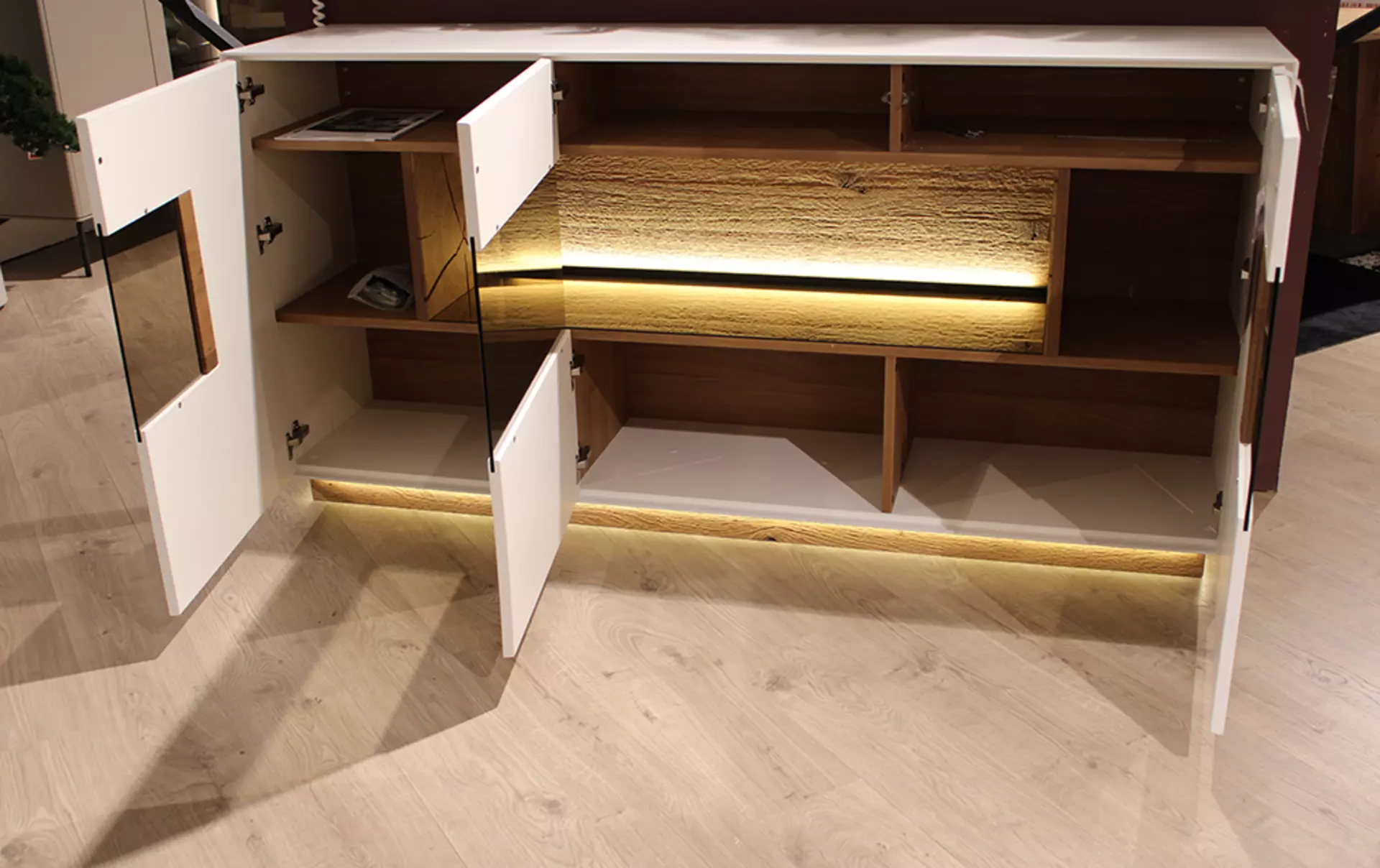 Weißes Sideboard mit geöffneten Türen und indirekter Beluchtung 