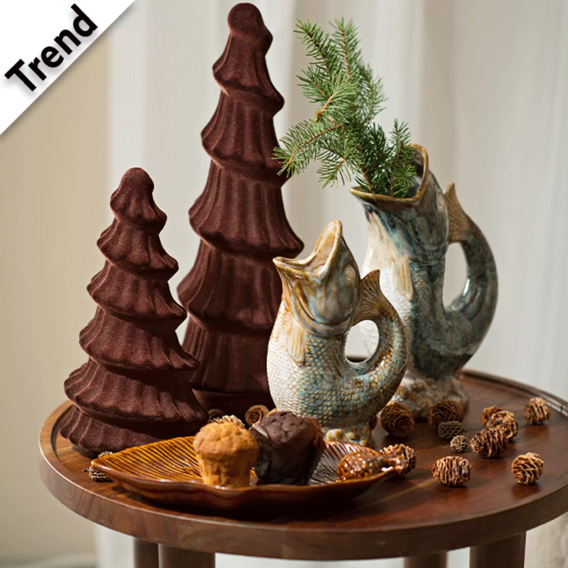 Moderne Weihnachtsdeko mit Tannenzweigen in Fischvasen und Kerzen in Tannenbaumoptik auf rundem Beistelltisch haus dunklem Holz