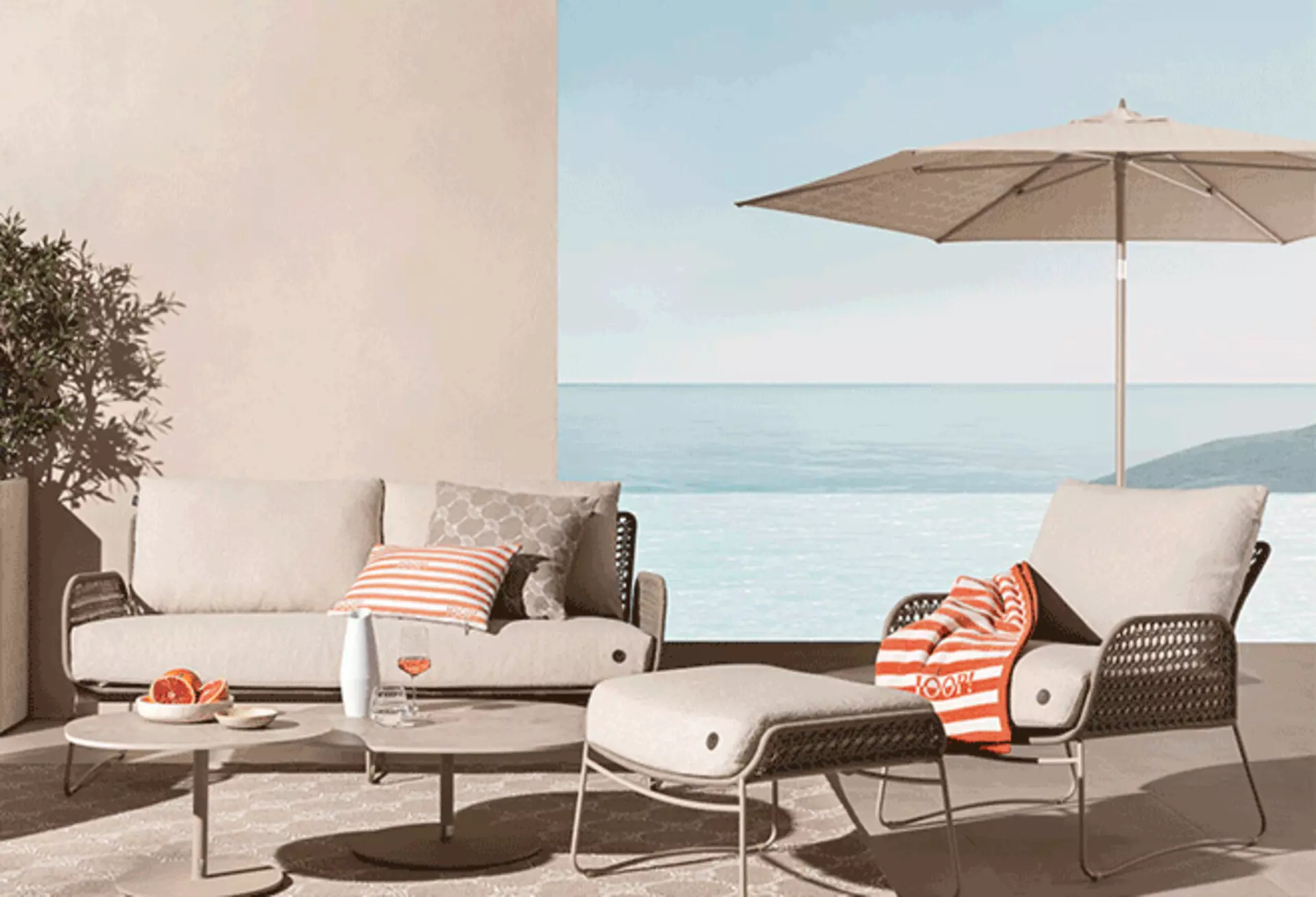 Cremefarbener Ampelschirm über Essbereich mit Gartenmöbeln nahe am Meer.