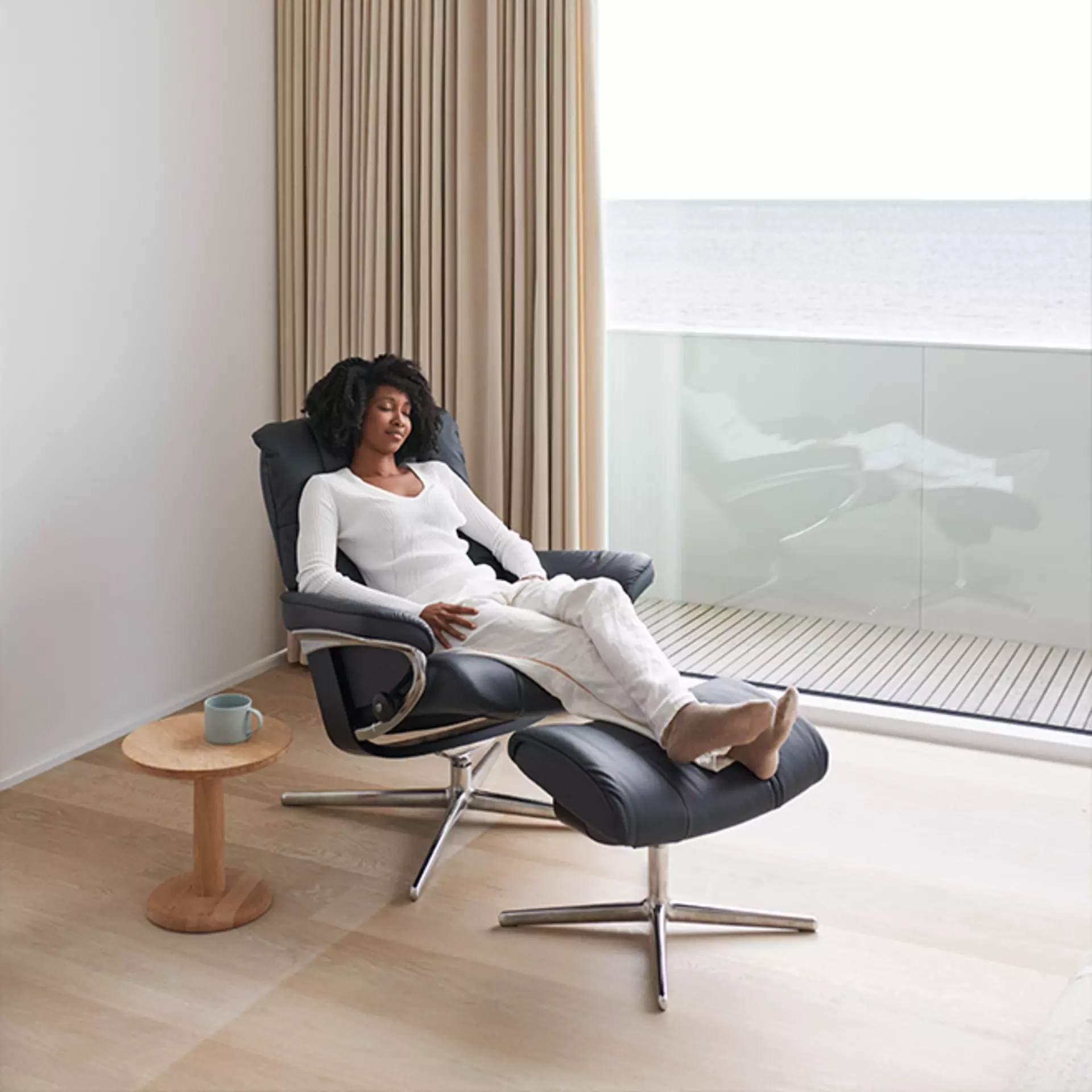 Eine Frau sitzt entspannt im Stressless Mayfair Sessel in shadow blue Leder gepolstert
