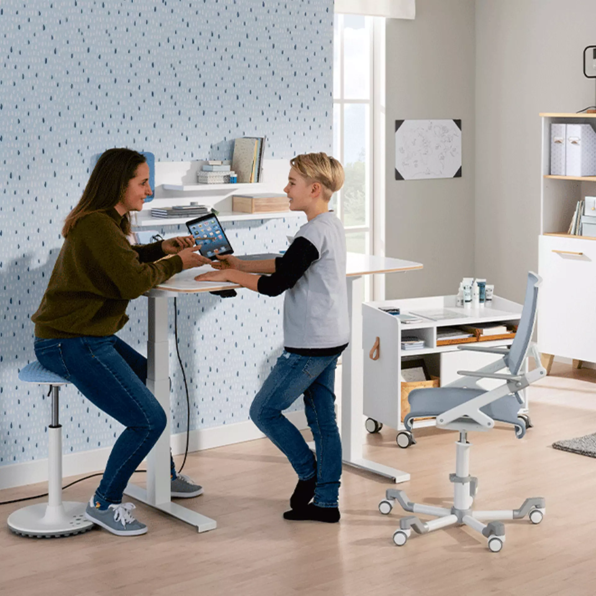 Kind und Mutter stehen an höhemverstellbarem ausgefahrenen Steh-Schreibtisch im Kinderzimmer