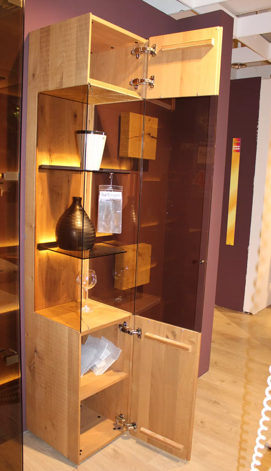 Vitrine in Holzoptik mit geöffneter Tür mit Dekoration