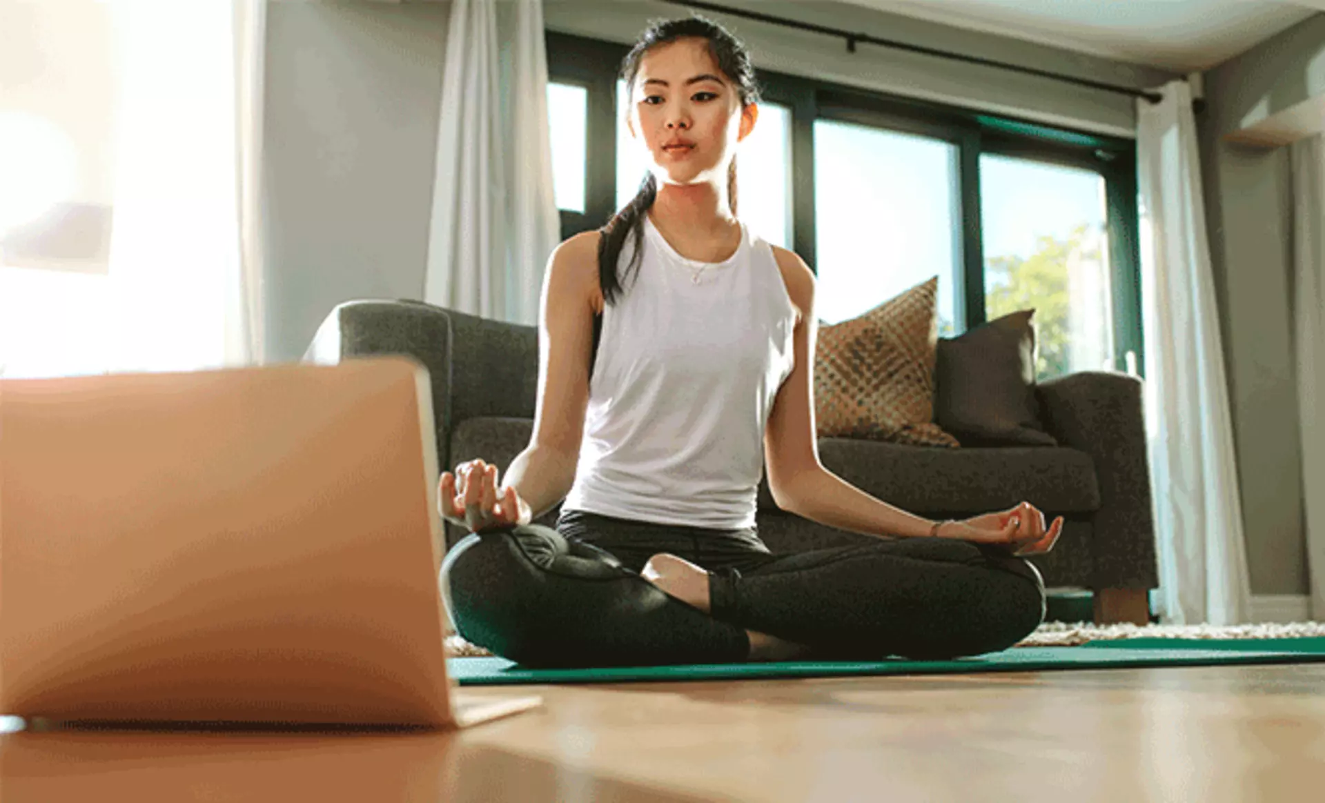 frau macht yoga mit laptop im wohnzimmer yoga bereich einrichten möbel inhofer