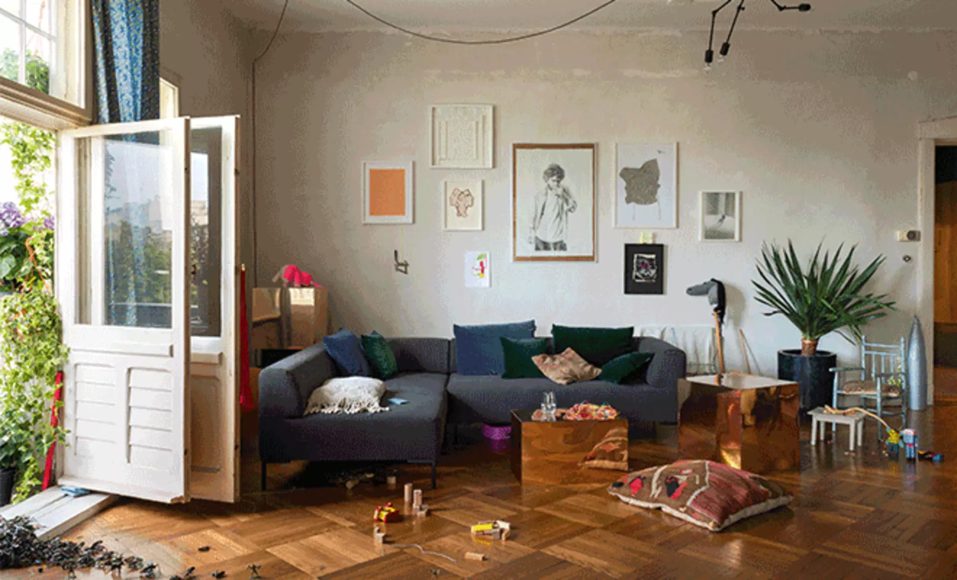 Dunkelgraues Freistil Sofa im familienfreundlichen Wohnzimmer mit Kunstwerken und Tageslich