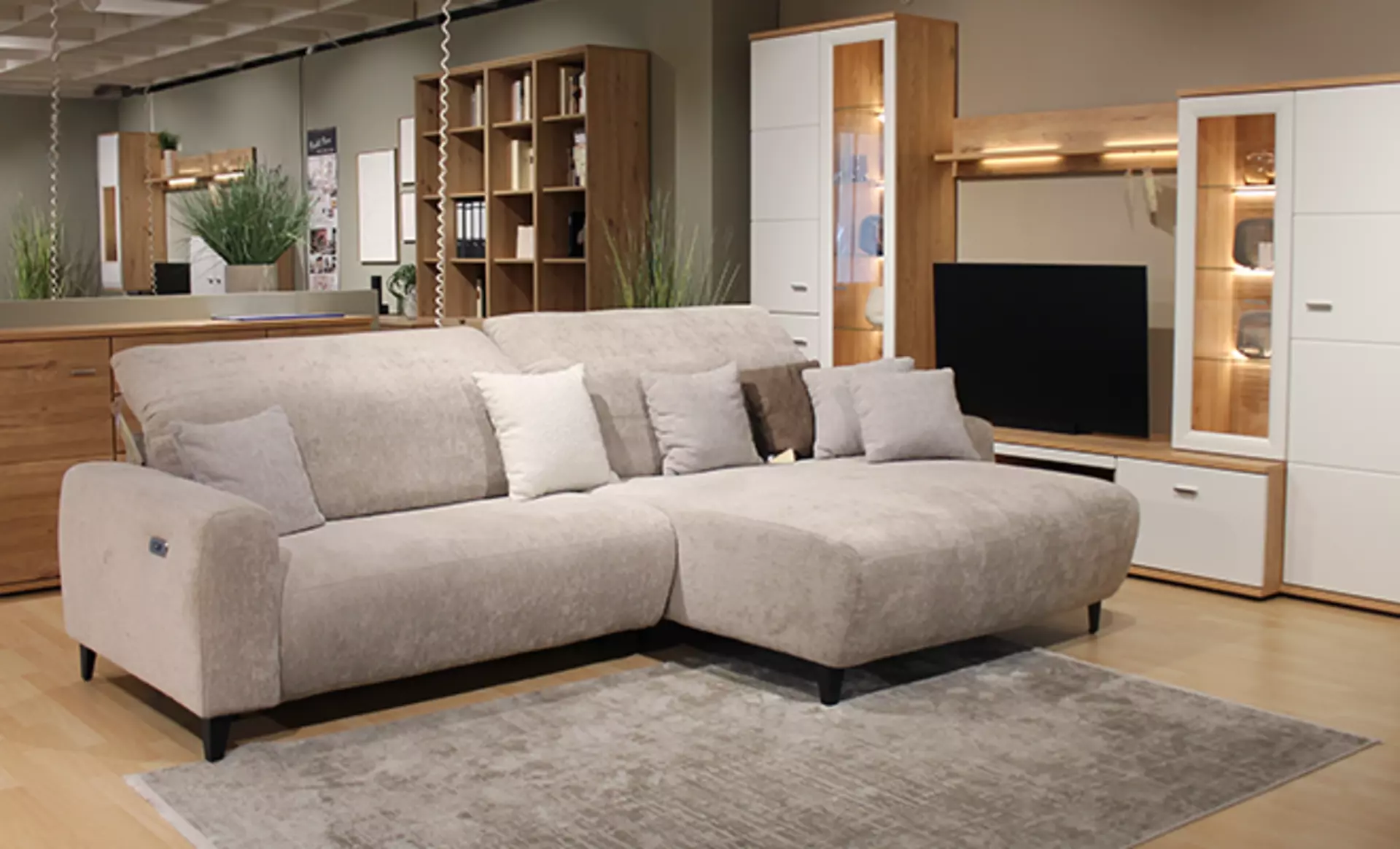 Helles L-Form Sofa vor einer Landhaus Wohnwand bei Möbel Inhofer