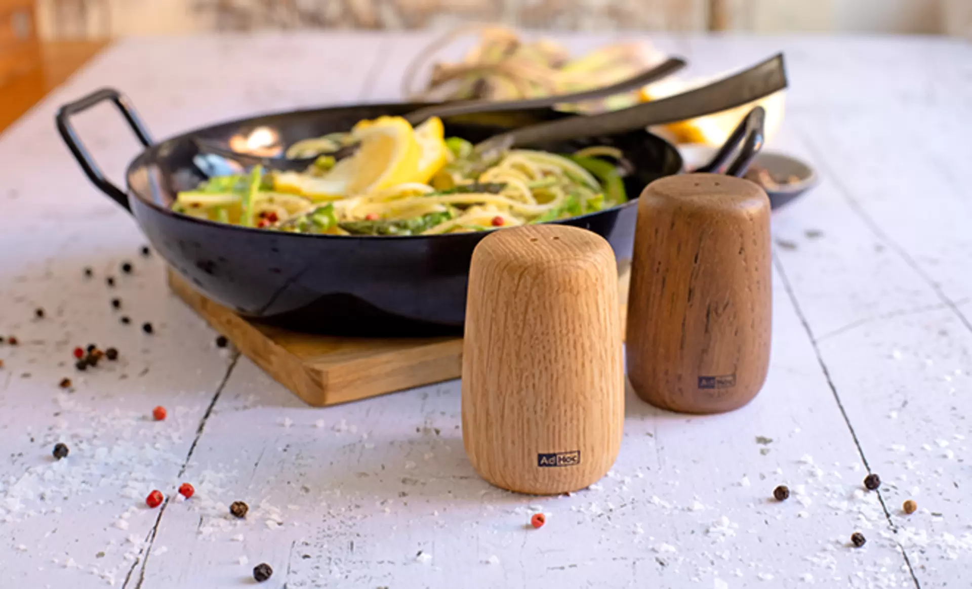 Die AdHoc Salz- und Pfefferstreuer der Serie Yoko aus Holz vor einem Teller mit Zitronenpasta abgelichtet